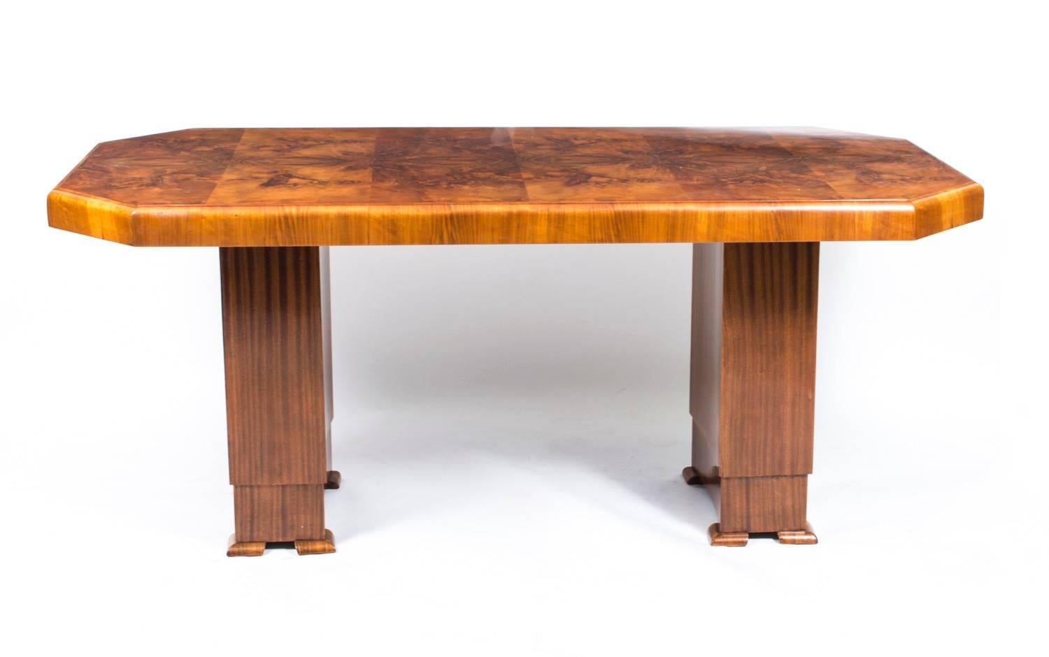 This beautiful antique Art Deco dining table dates from 1930. Crafted in burr walnut, it can comfortably seat six people.

Standing on twin pedestal supports which terminate in four contrasting colour wooden feet on each pedestal, this antique