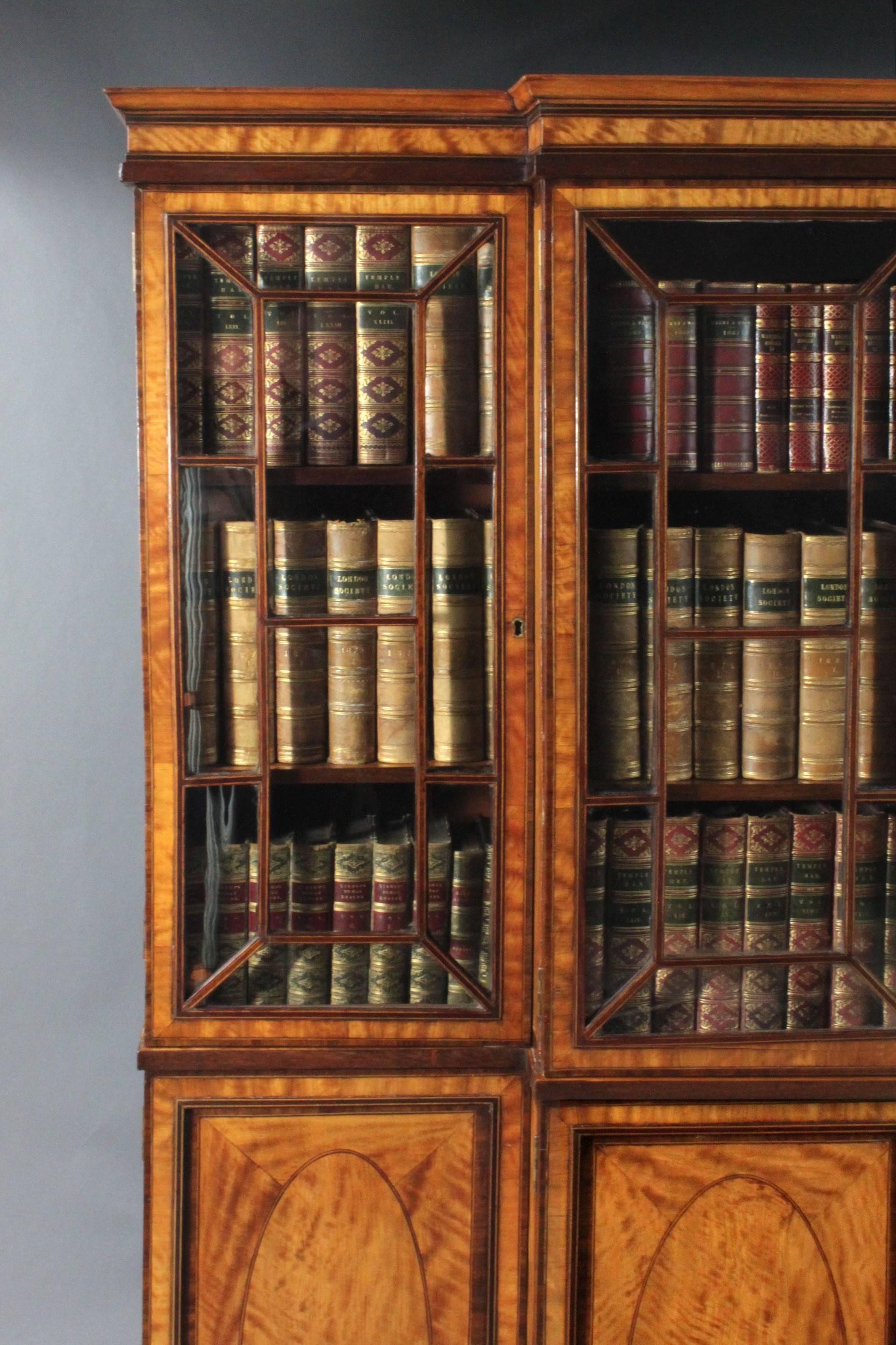 An exceptional George III Sheraton period small breakfront bookcase: Veneered in satinwood with purple-heart inlay, kingwood crossbanding and box wood and ebony stringing.