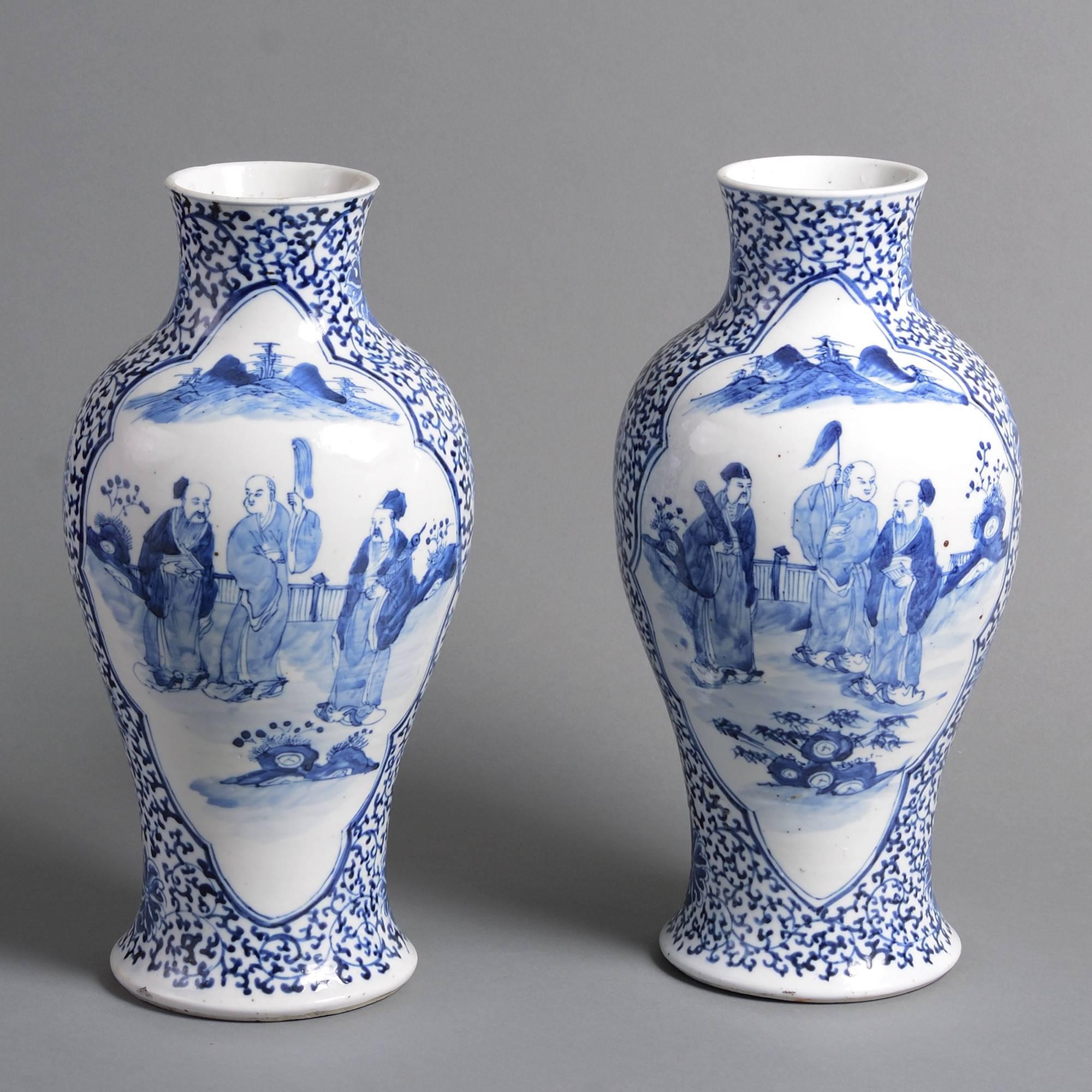 A pair of late 19th century blue and white porcelain baluster vases, the bodies with foliate grounds and figurative cartouches.
