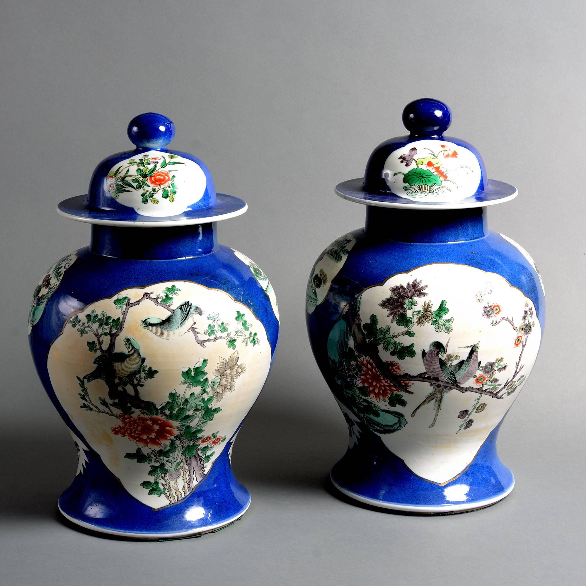 A pair of 19th century porcelain baluster vases and covers, each with cartouches of birds and flowers set upon a powder blue ground.

Qing Dynasty, Tongzhi period.

One rim crack and hairline restored to neck.
