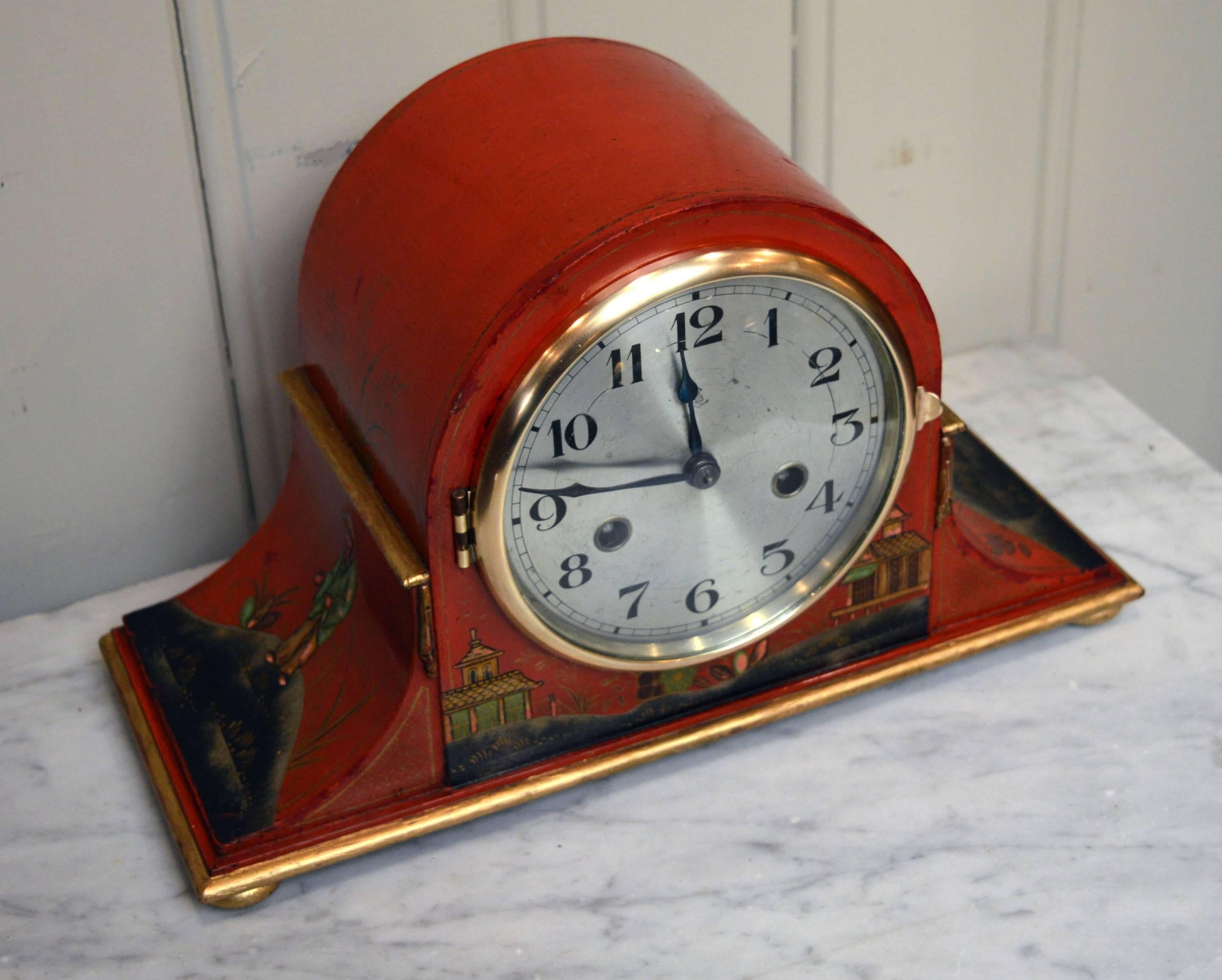 A George V period mantel clock, having a dome top case, a red ground with raised oriental style decoration. The polished steel dial has a convex glass. The 8 day pendulum movement strikes the hours and halves on a gong and was made by Gutav Beker of