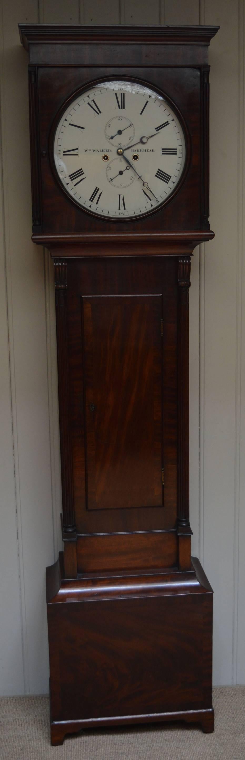 A Regency period Scottish mahogany longcase clock. It has a typical West Coast of Scotland case, with a flat top, a 14 inch white enamel dial with reeded hood and trunk pillars and bracket feet. The dial has a subsidiary date and seconds dial and is