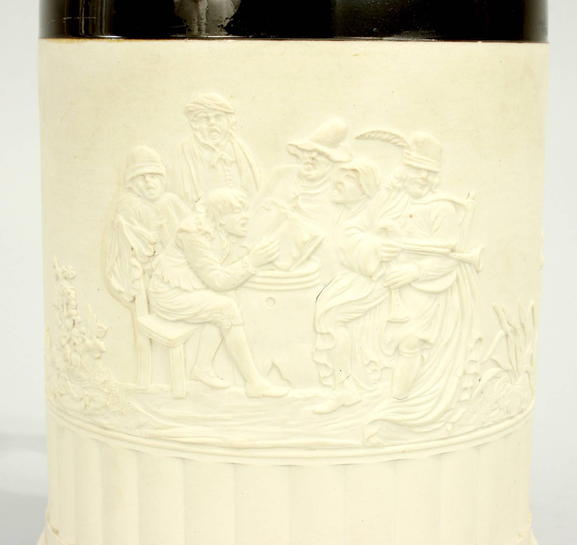 Large Adams white stoneware tankard / mug.
A large white stoneware tankard by Adams. The mug has a large handle and a plated metal rim made by Thomas Law & Co. The scene is in relief and depicts a group of merry men having a sing song seated around