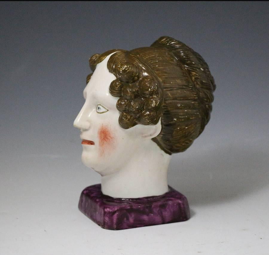 A very rare English pearlware pottery bust probably representing Queen Charlotte the wife of King George 111. The head is modelled on a square base which is decorated with purple enamel. 
The rendition is very naive and striking with strong