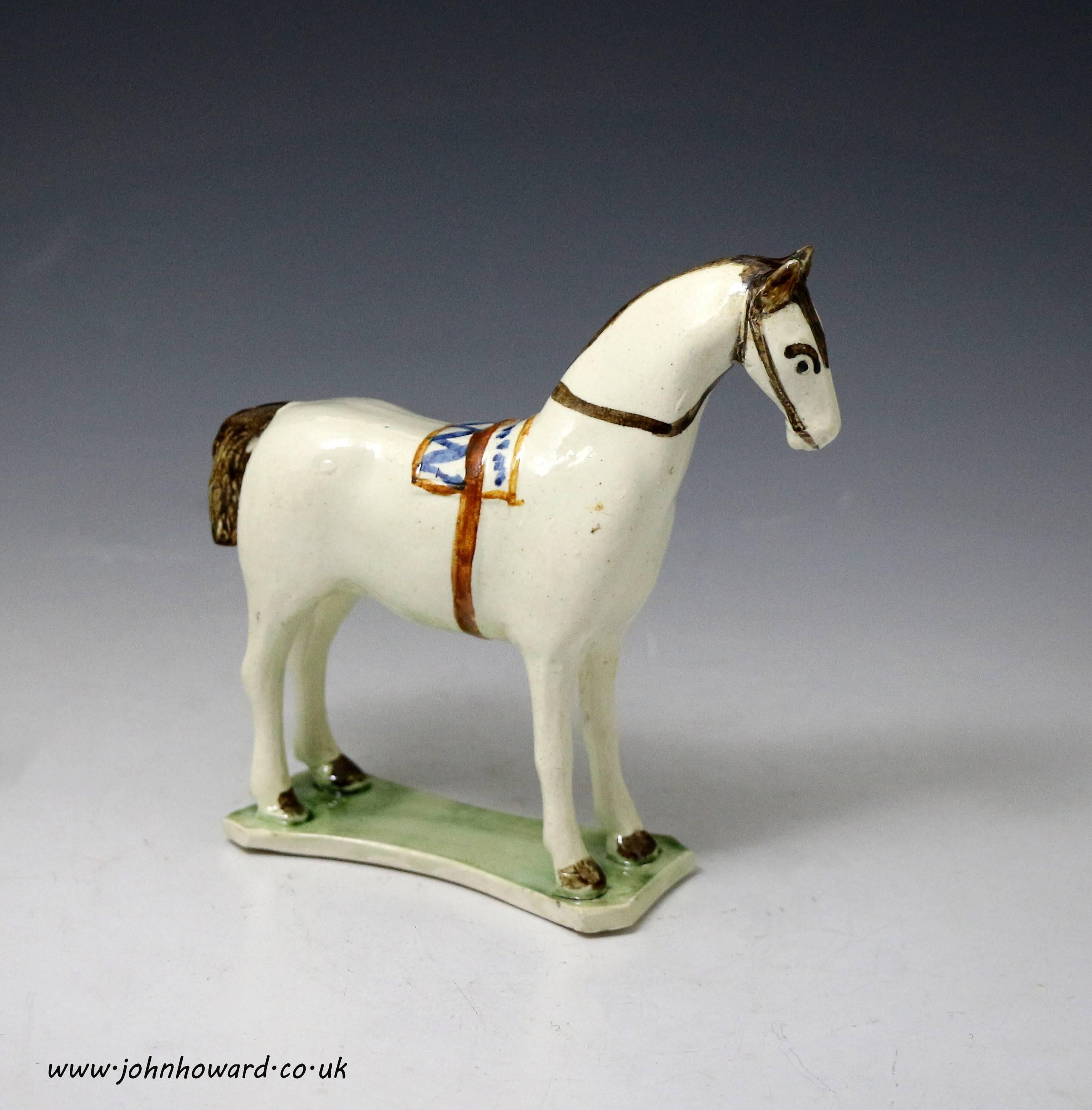 A wonderfully naive figure of a saddled horse standing on a green base. The figure is simply decorated in pratt colours. This rare figure is in remarkably fine condition.