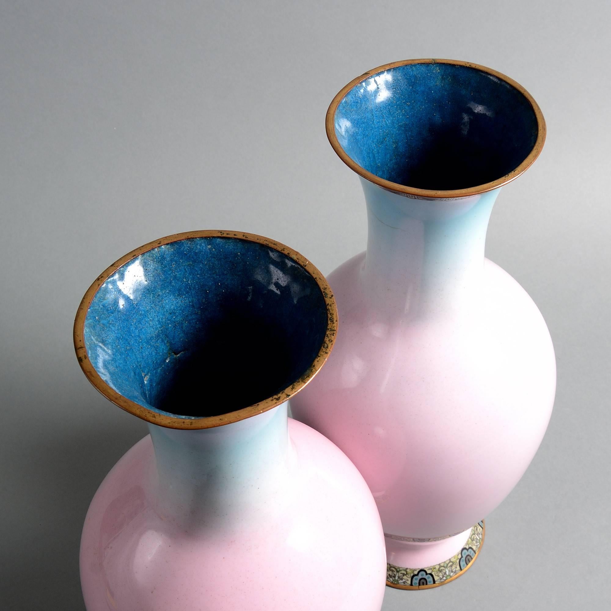 A fine late 19th century pair of cloisonné baluster form vases, enameled with soft blue and pink and set upon an intricately decorated foot.