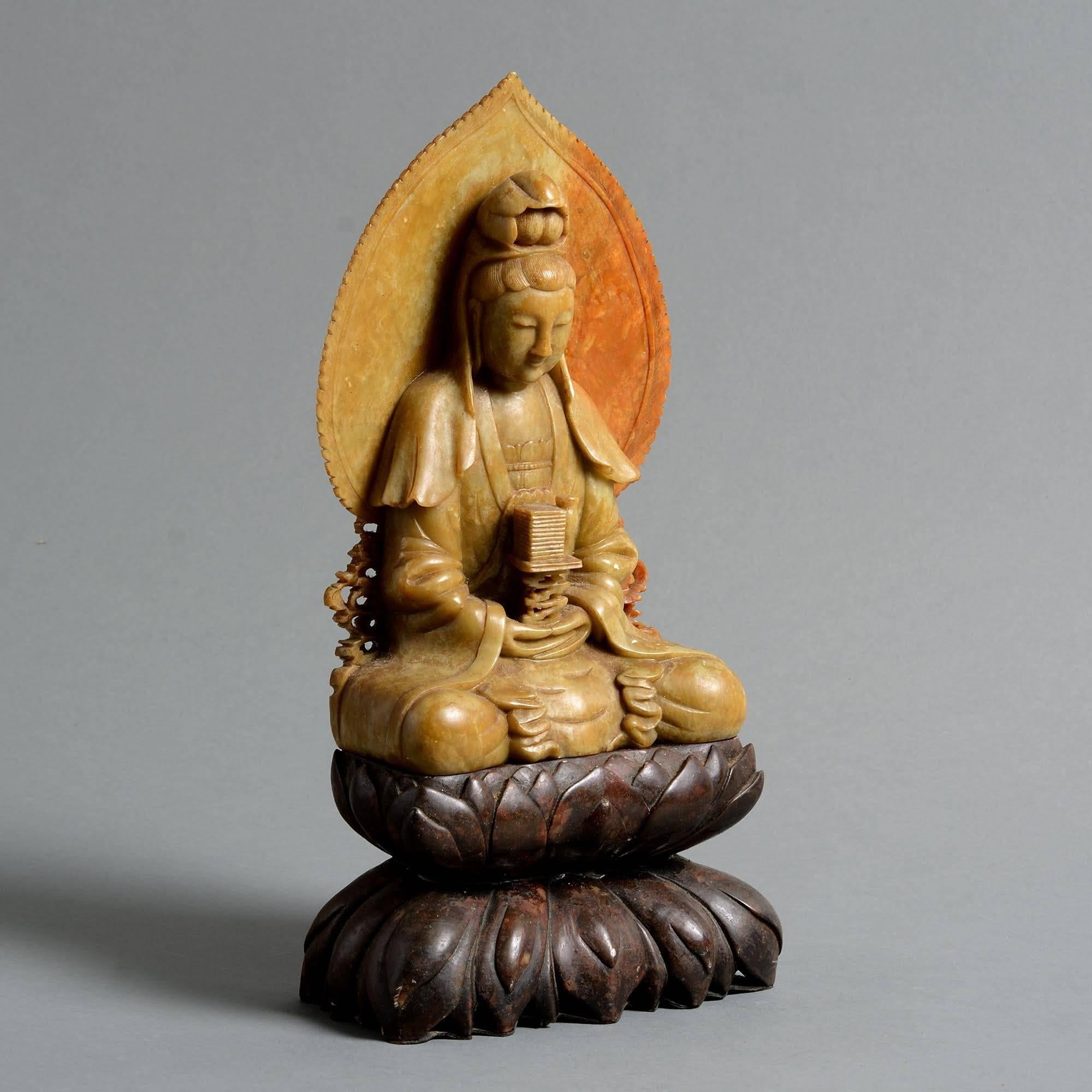 A fine late 19th century carved soapstone Quan Yin, set upon a hardwood base.