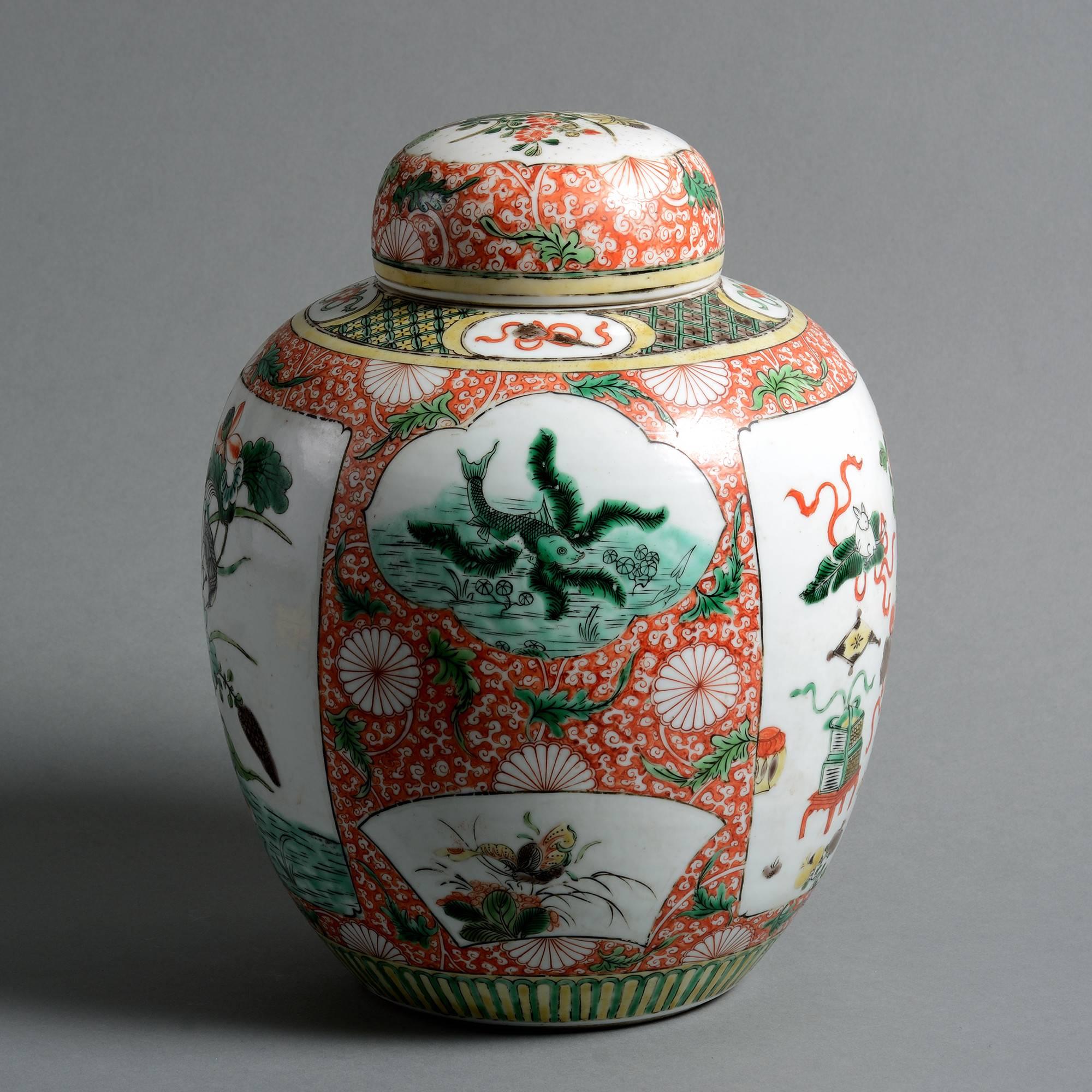 A late 19th century Famille verte jar with cover, of bulbous form, with cartouches depicting antiques, flowers, birds and insects set upon a ground of coral red and white vermicelli.

Qing Dynasty, Guangxu period.
