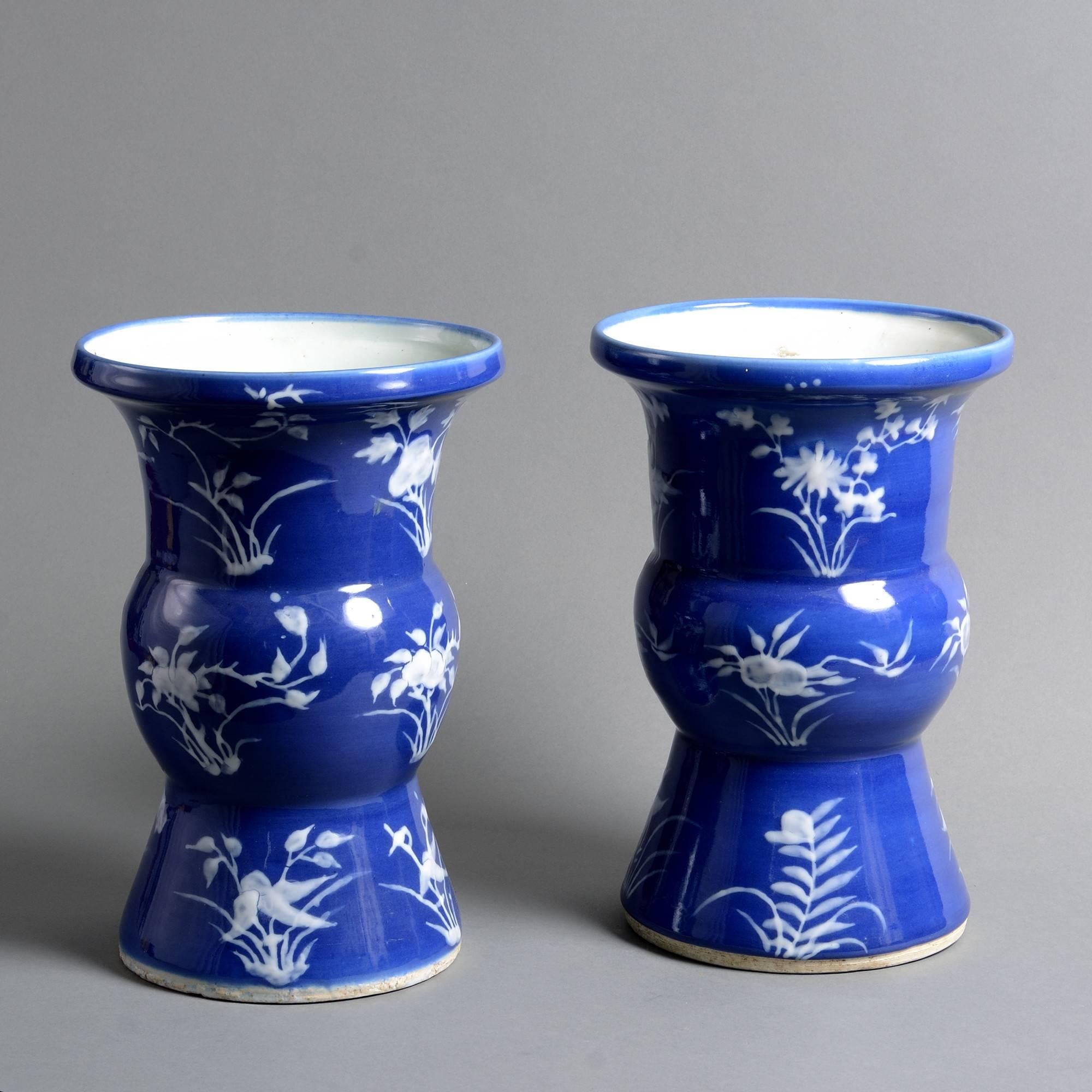 A 19th century pair of porcelain beaker vases, the bodies decorated with white stylized flowers upon a rich blue ground. 

Qing dynasty, Tongzhi period.