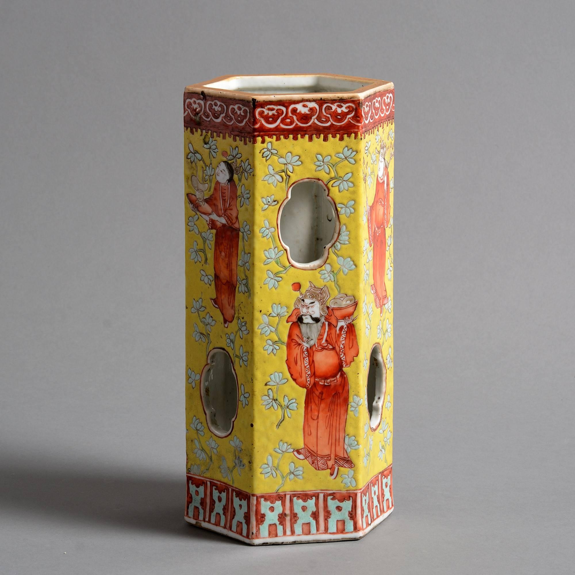 A 19th century porcelain hat stand of hexagonal form, having a pierced body, with figurative decoration in red and turquoise glazes upon a yellow ground. 

Qing dynasty.