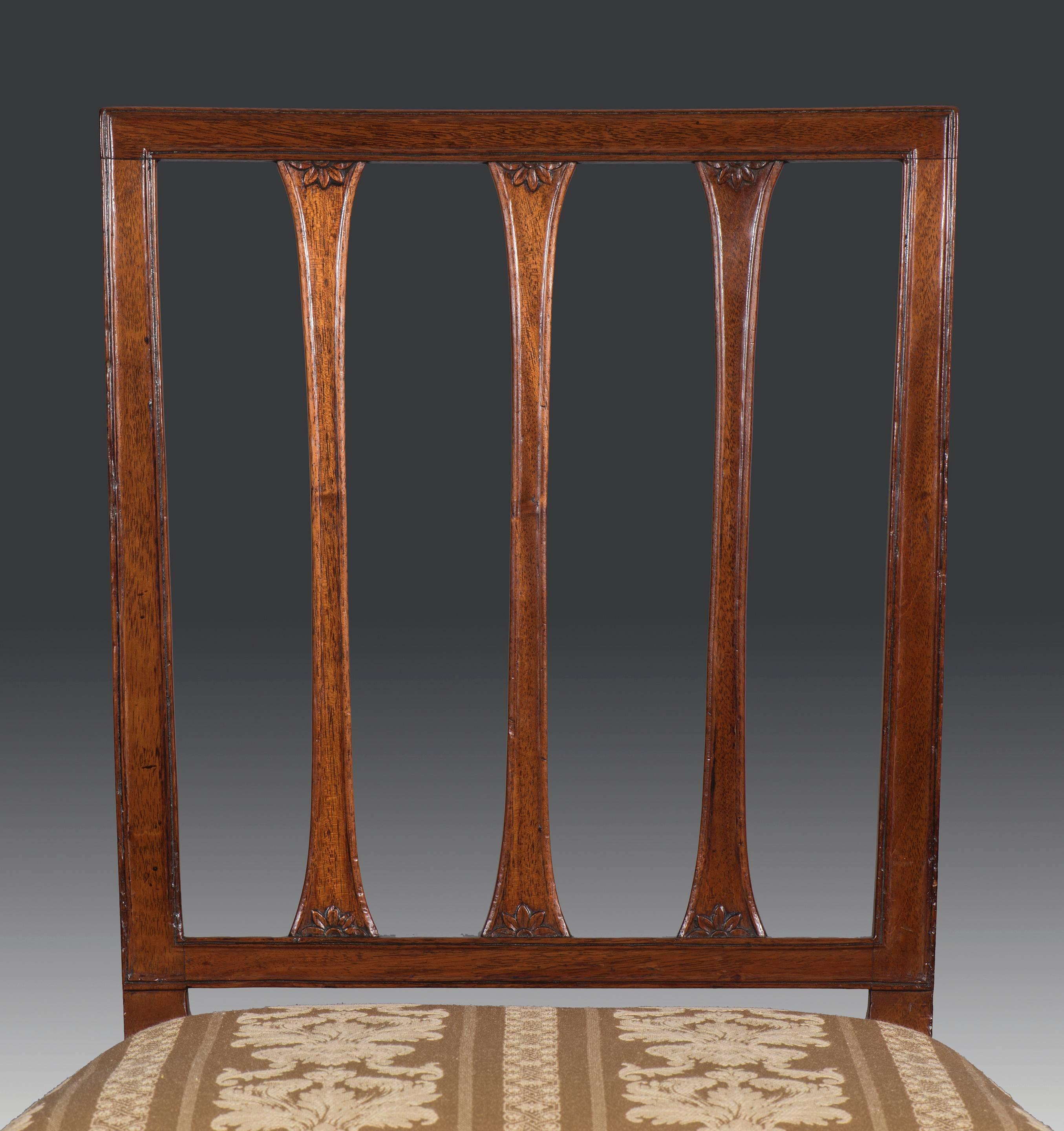 Set of 12 (10+2) George III period mahogany 18th century dining chairs with ten single chairs and 'his and hers' carvers. The rectangular bar backs with shaped and carved flower heads to the supports are elegant and very typical of the day. The