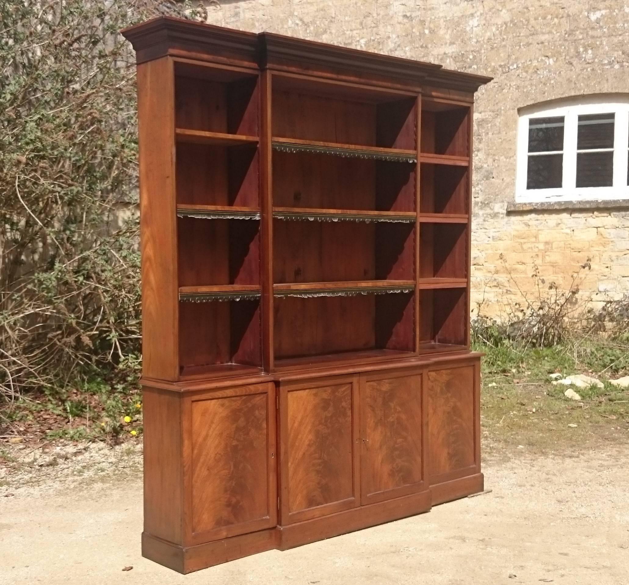 Mahogany antique breakfront bookcase with flame mahogany door fronts and open top. This is a good large scale bookcase made of very good quality timber and with adjustable shelves. This is a magnificent piece of furniture and less expensive than