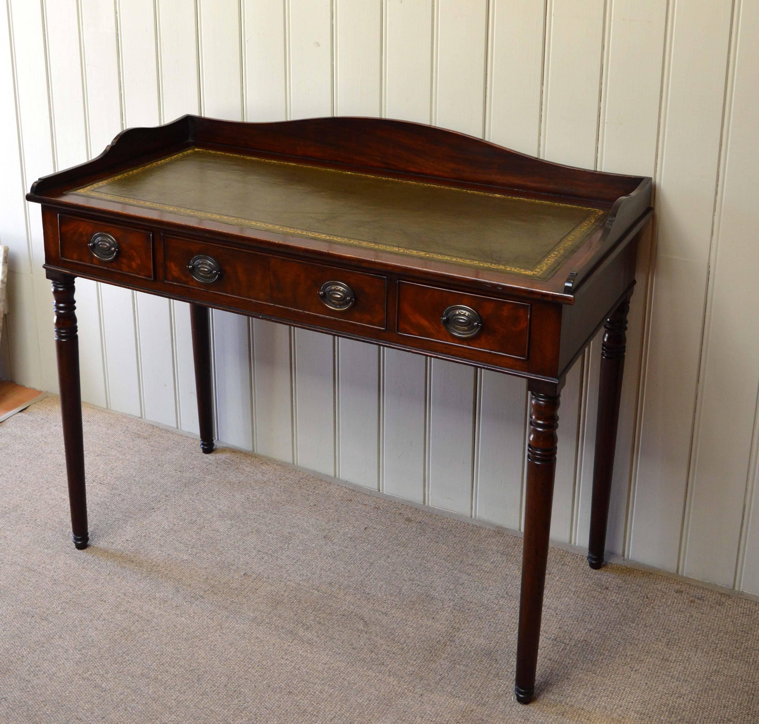 Victorian mahogany writing desk having a central drawer flanked by two smaller with a leather top and upstand, supported by turned legs.