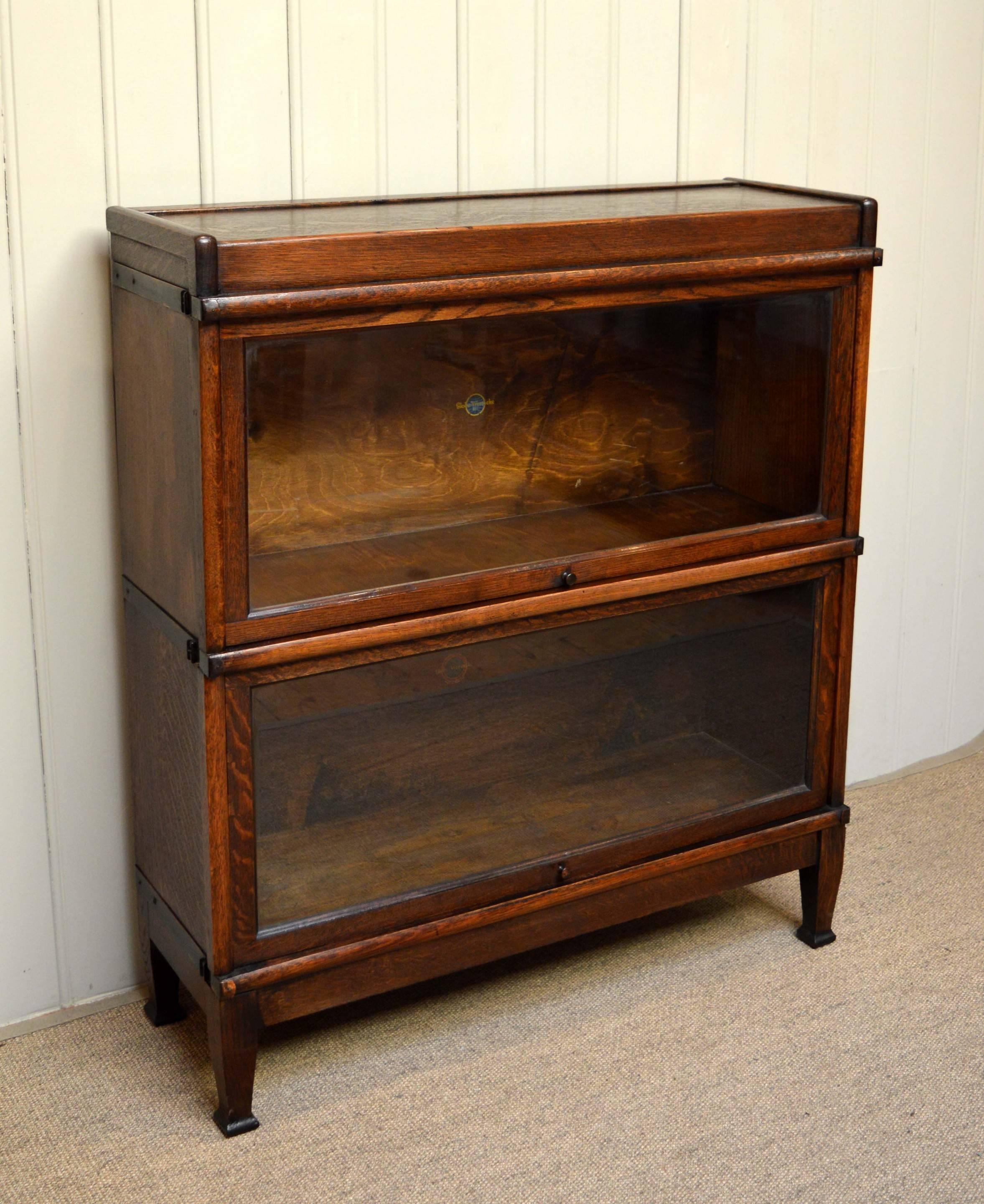 Two-tier oak Globe Wernicke bookcase having up and over glazed doors raised on straight tapering legs with spade feet.