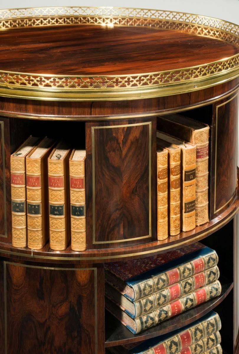 A very rare freestanding circular rosewood bookcase inlaid throughout in brass. Note the gallery in the Gothic design and the wonderful carved wood lion paw feet on concealed castors. English, circa 1820. 
Free standing bookcases became a