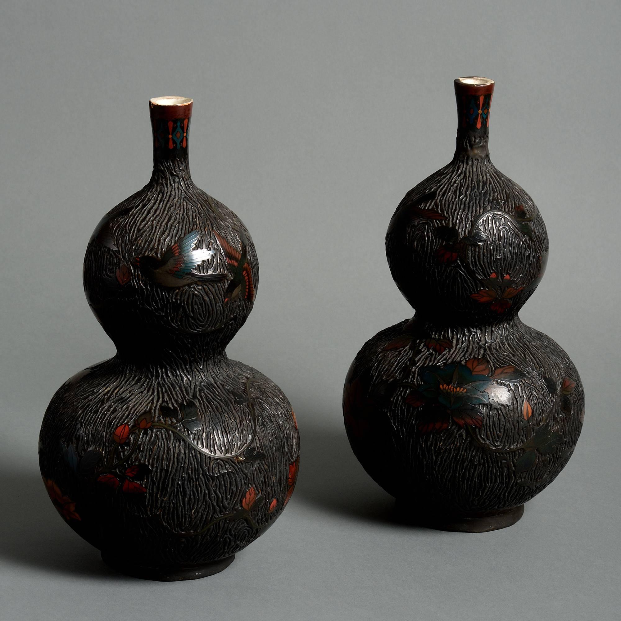 A pair of 19th century pottery vases of double gourd form, decorated throughout with floral and ornithological cloisonné work in red and blue enamels,

Meiji period (1868-1912).