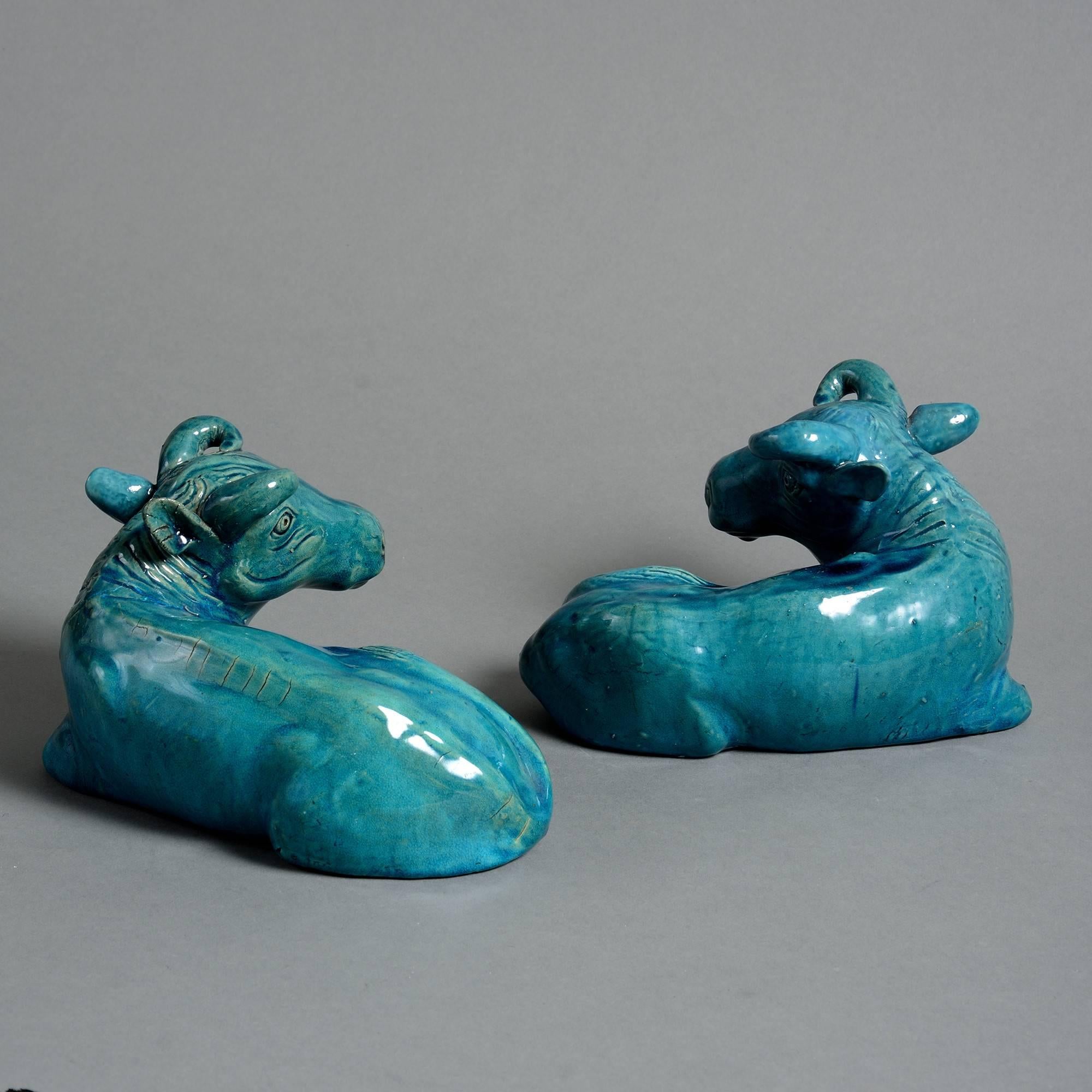 A pair of late 19th century turquoise glazed porcelain buffalo, of stylized form and modeled lying down,

Qing dynasty, Guangxu period (1875-1908).