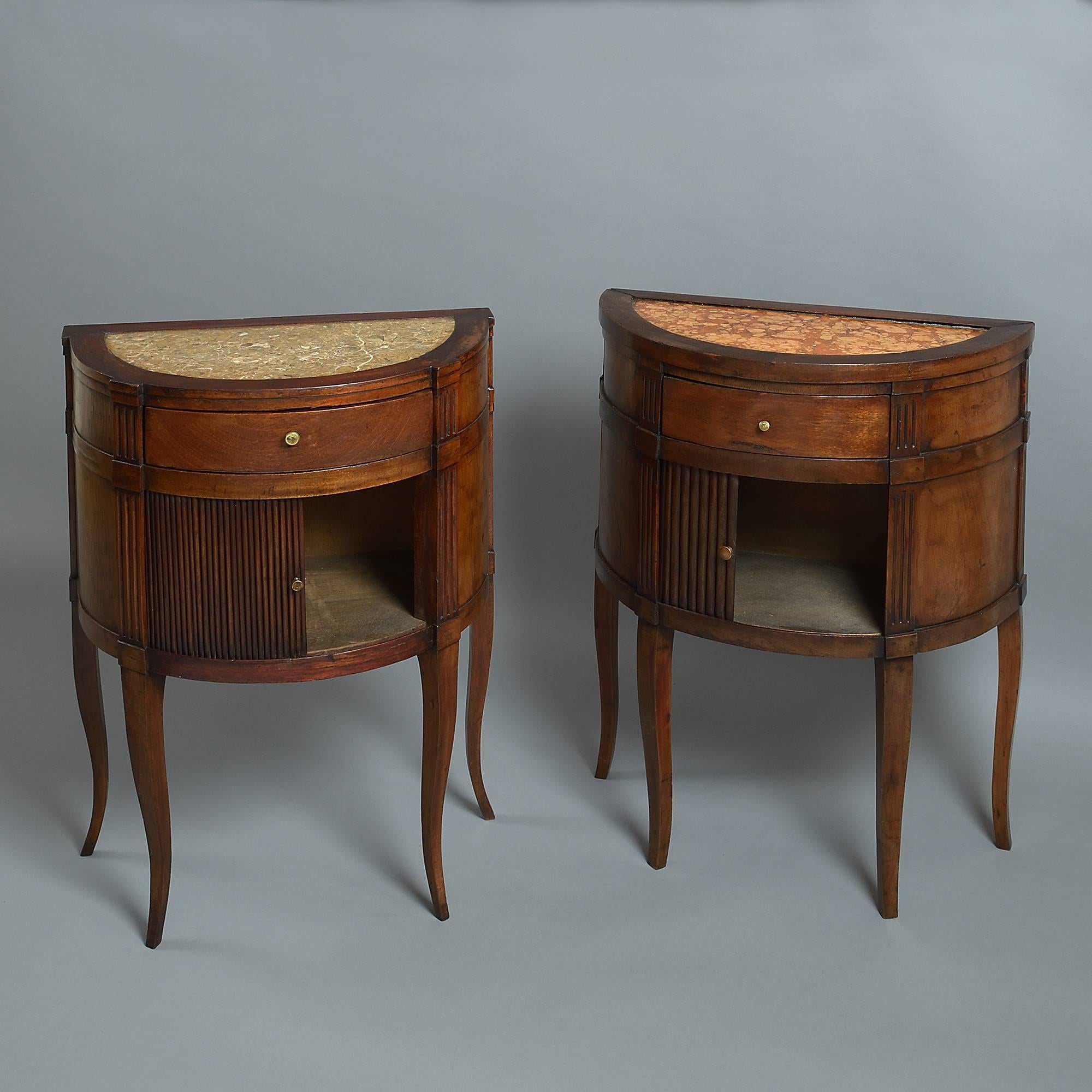 A matched pair of Directoire period walnut commodes of demilune form, having inset marble tops, with pilasters and tambour fronts and standing on shaped tapering square legs.

Height of second commode: 30 3/4 inches (78.1 cm) 
Width of second