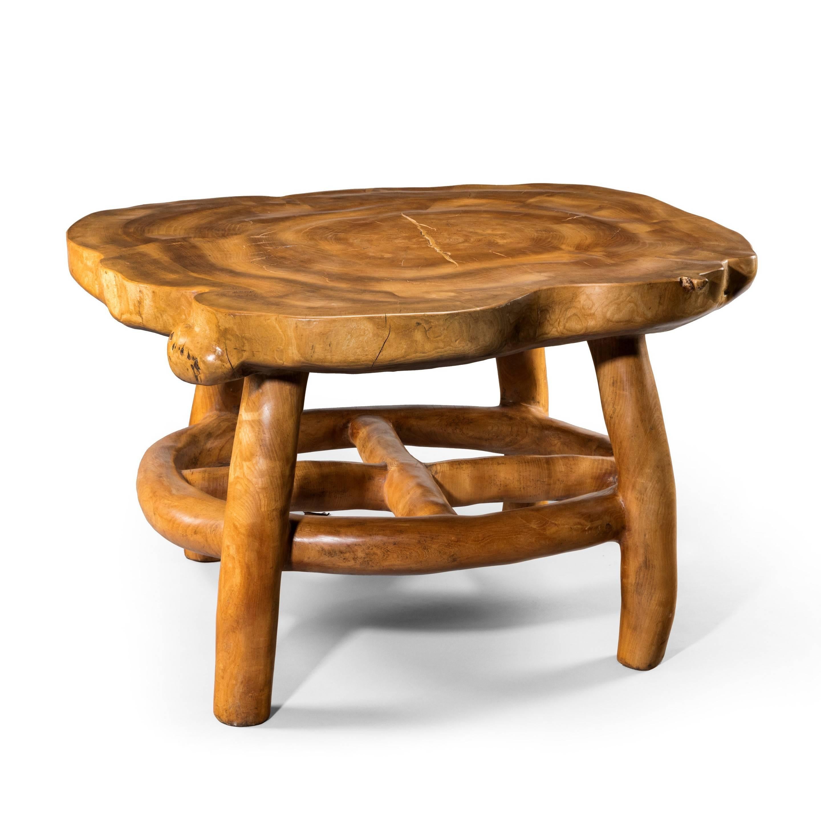 An unusual and attractive centre table by Maxie Lane, 
carved from solid elm with an irregular shaped top supported by four bowed legs and a circular cruciform stretcher.