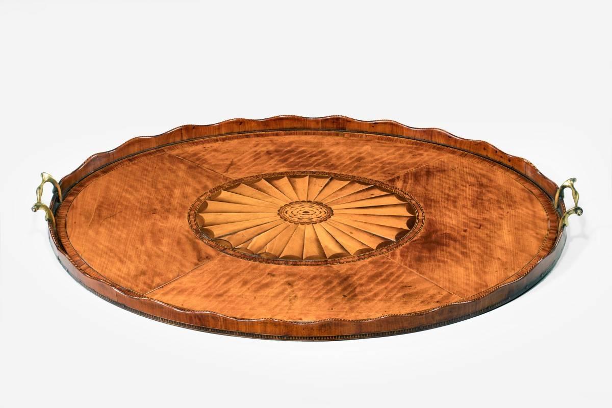 Satinwood tray. 18th century oval Georgian satinwood veneered tray with crossbanded bandings. Original gilt brass carrying handles, wavy edged laminated raised gallery, chequered inlaid decoration, English, 1780.