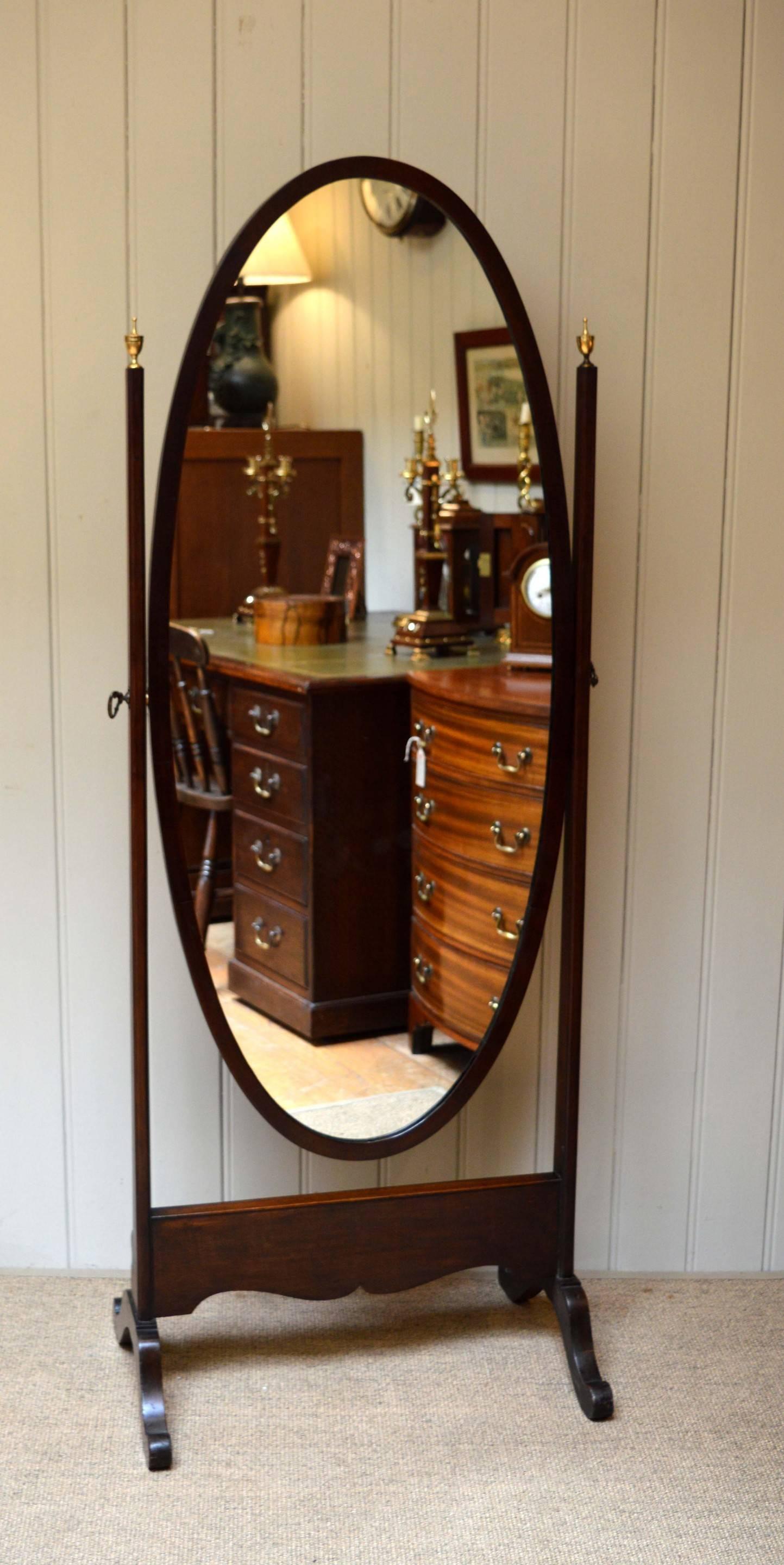 Edwardian oval mahogany mirror having brass finials standing on outsplayed supports.