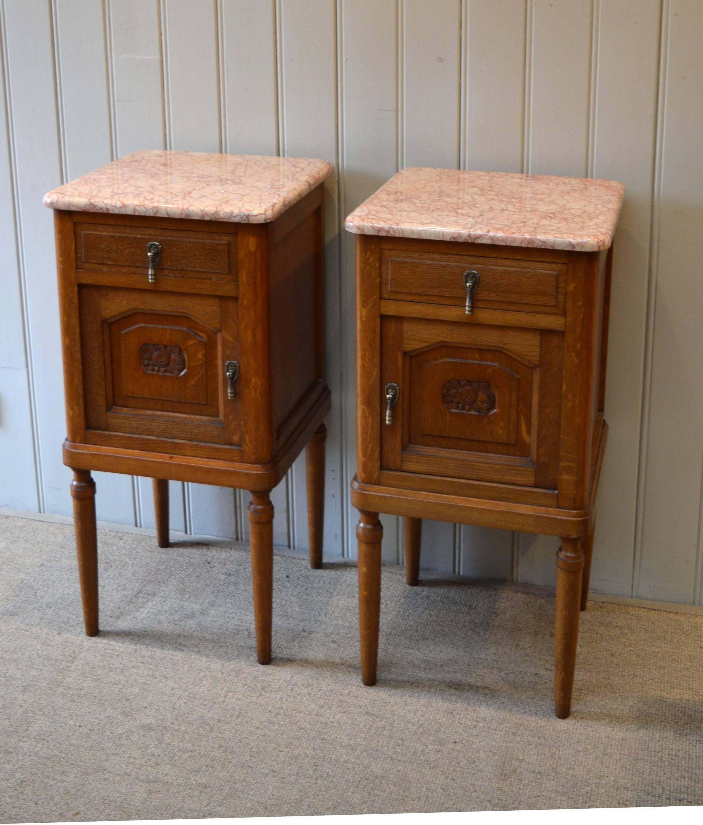Pair of oak marble-top bedside cabinets having a single drawer above a cupboard base with rouge marble tops and raised on turned wooden legs.