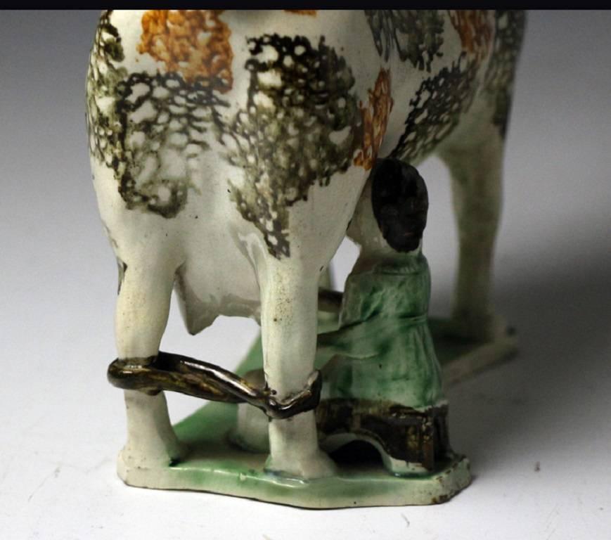 Antique pottery hobbled legged cow creamer complete with the figure of a milking maid.
This creamer figure would date to the beginning of the 19th century.
Classic early features a fine thin base, good potting and decoration with a good pearlware