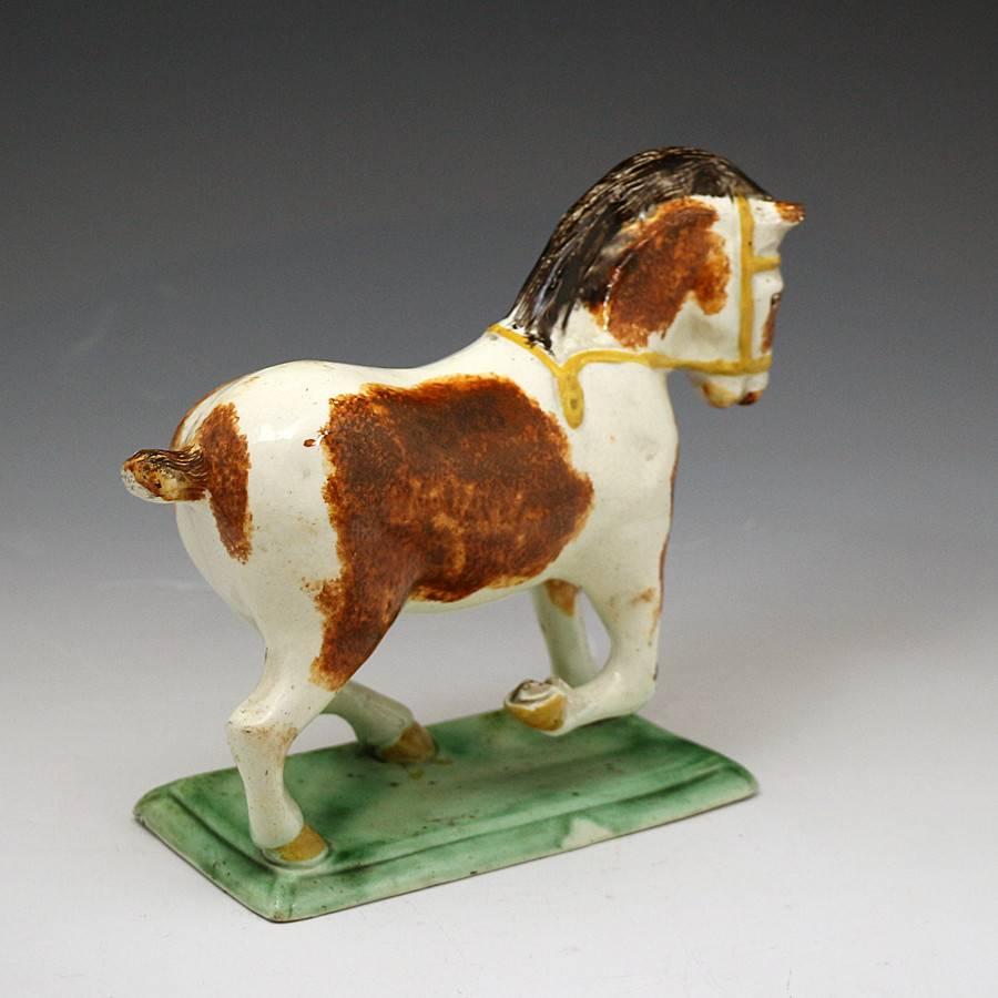 A rare pottery figure of a Suffolk Punch modelled standing on a base.
The figure is decorated with under colour glaze and dates from the late 18th century.
