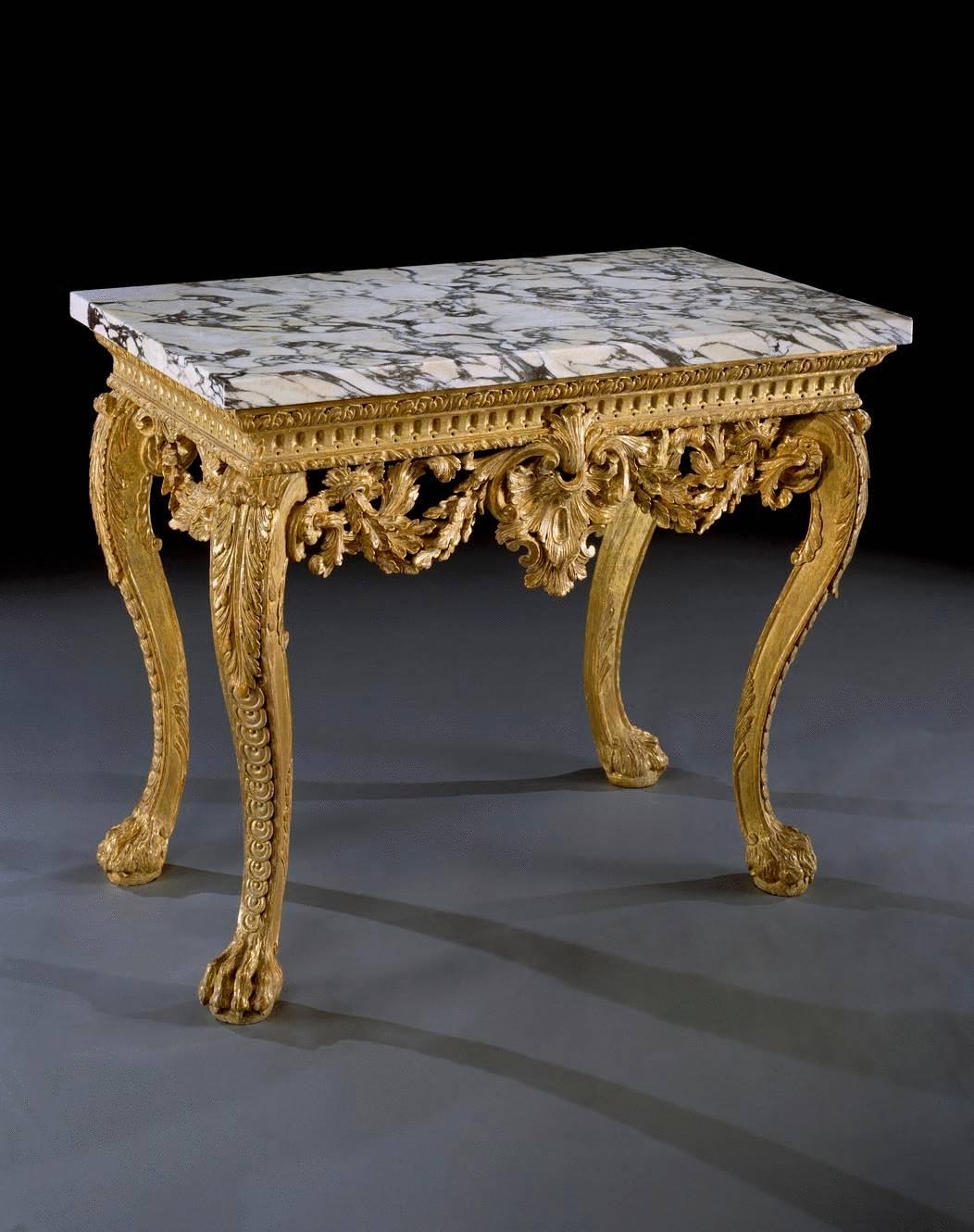 A rare and important pair of early 18th century carved giltwood side tables in the manner of William Kent. The rectangular replaced ‘brèche de Medici’ marble tops on moulded apron with stiff leaf carving centred by a finely carved Venus shell
