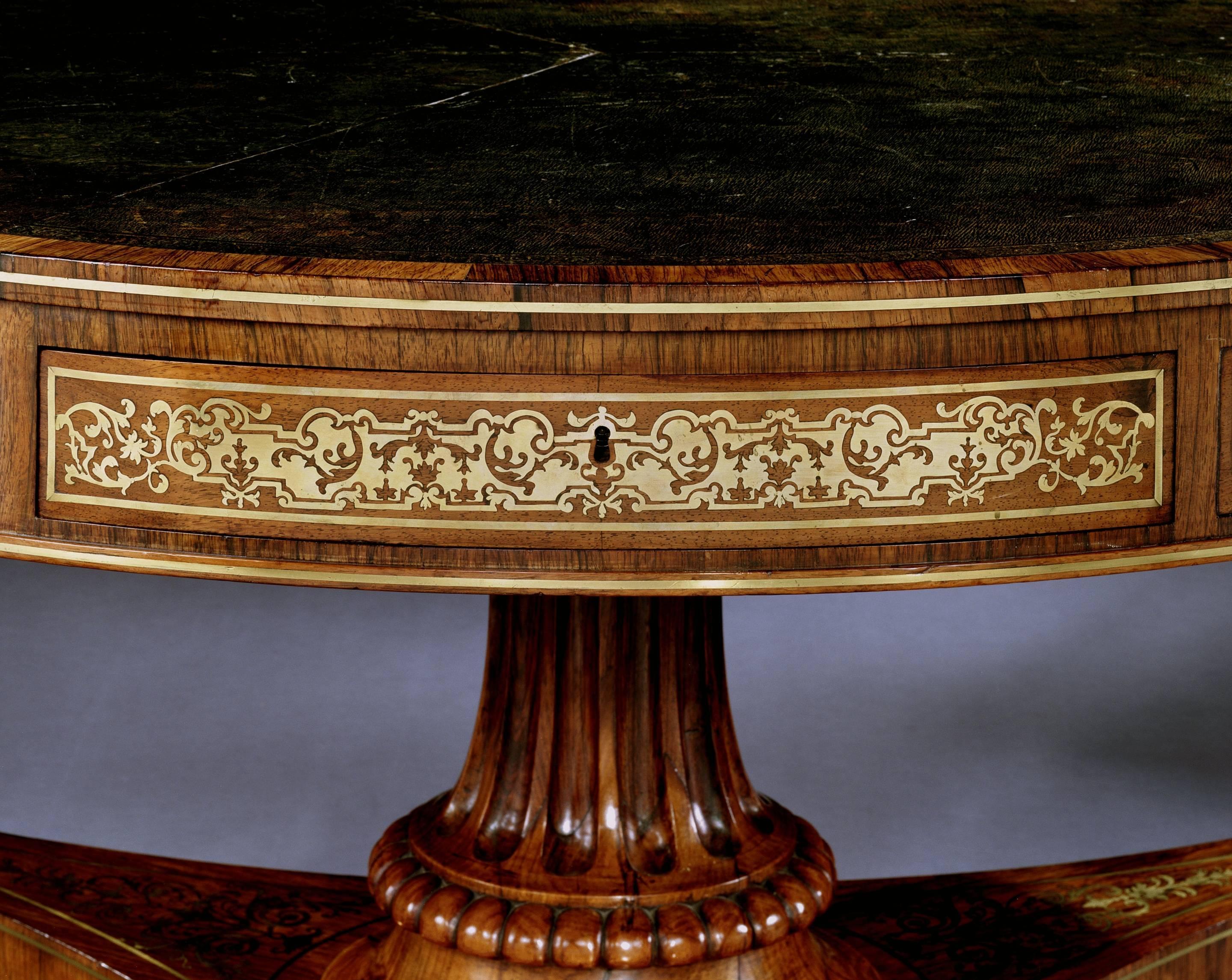 An important early 19th century brass inlaid rosewood drum table of fine quality, the circular black tooled leather lined crossbanded top above frieze drawers with panels of scrolling foliate boulle inlay, on a fluted waisted column supported by a
