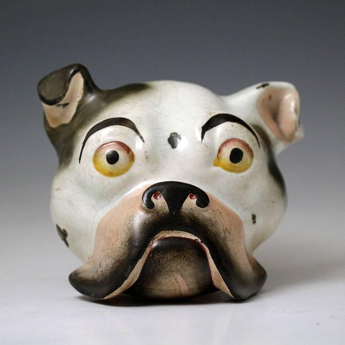 A rare pearl ware pottery stirrup cup in the form of a bull terrier's head. The cup is very strongly modelled and captures the pugnacious characteristics perfectly, the dog sports an orange collar with gilt buckle. Dates to the early 19th century