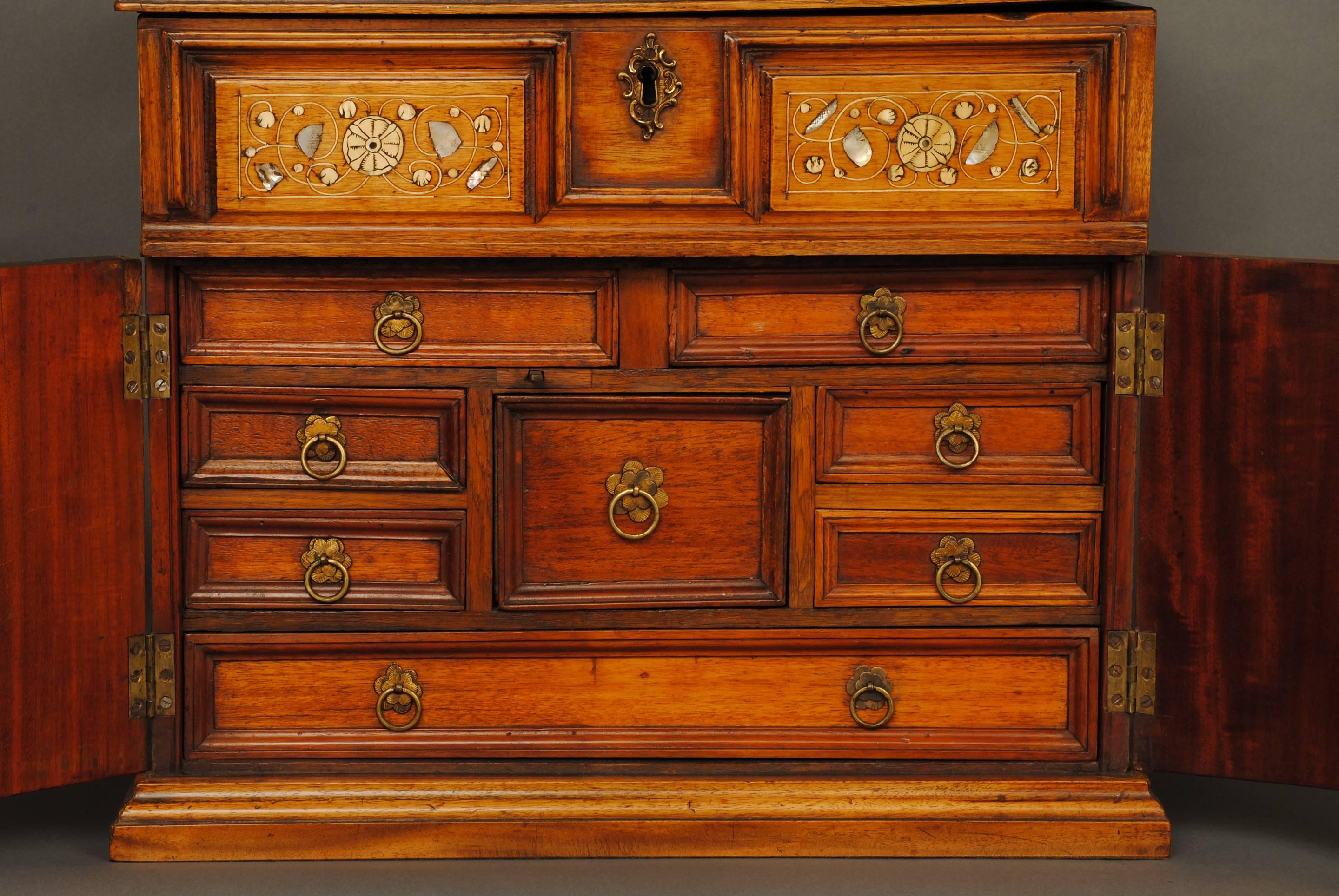 A 17th century walnut two-door cabinet inlaid with engraved bone and mother-of-pearl in floral design, the two doors open to reveal a fitted interior.