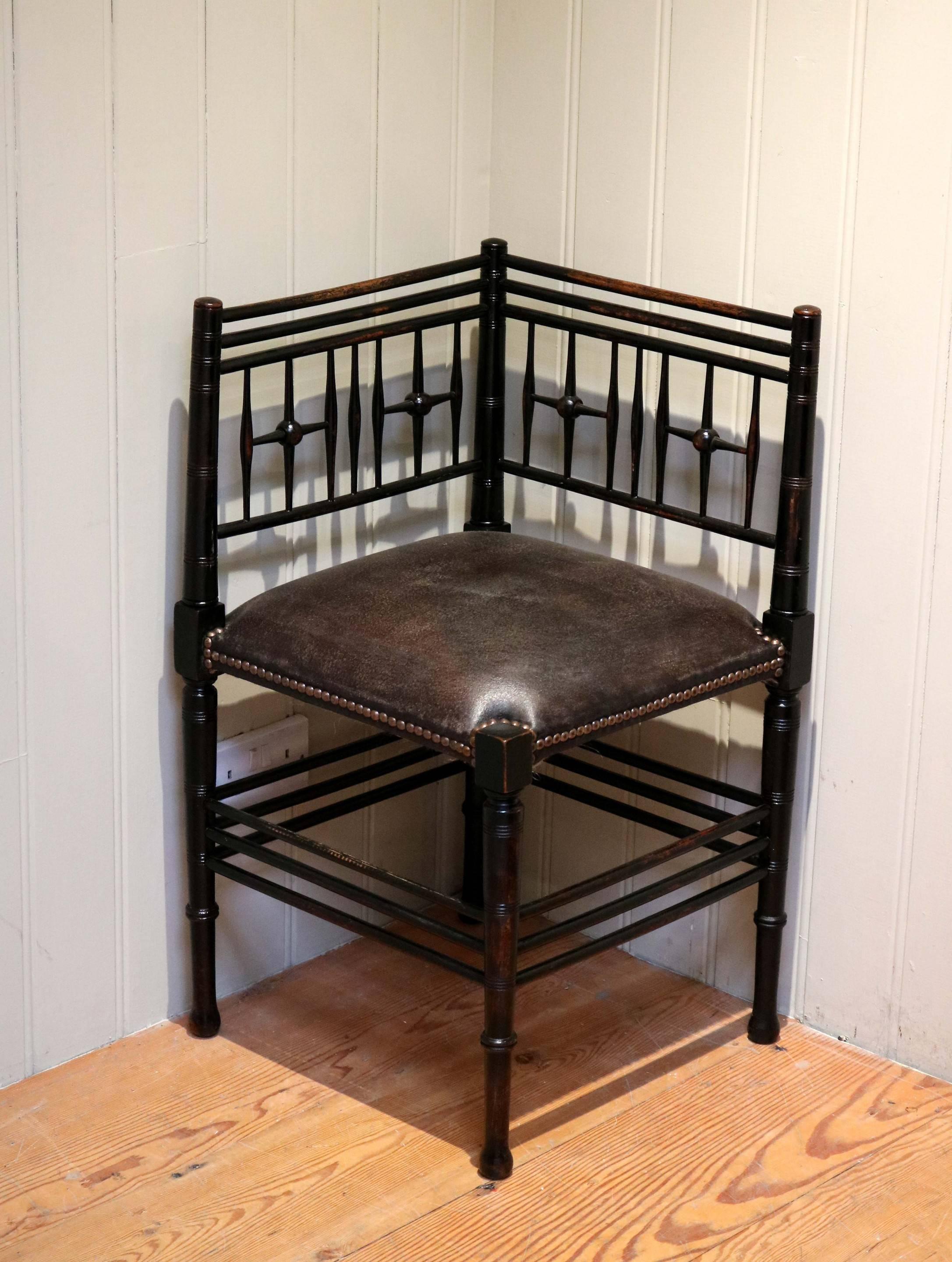 Ebonized corner chair having a upholstered leather seat. This chair was retailed by Liberty & co as part of the Argyll suite designed by Ford Maddox Brown.