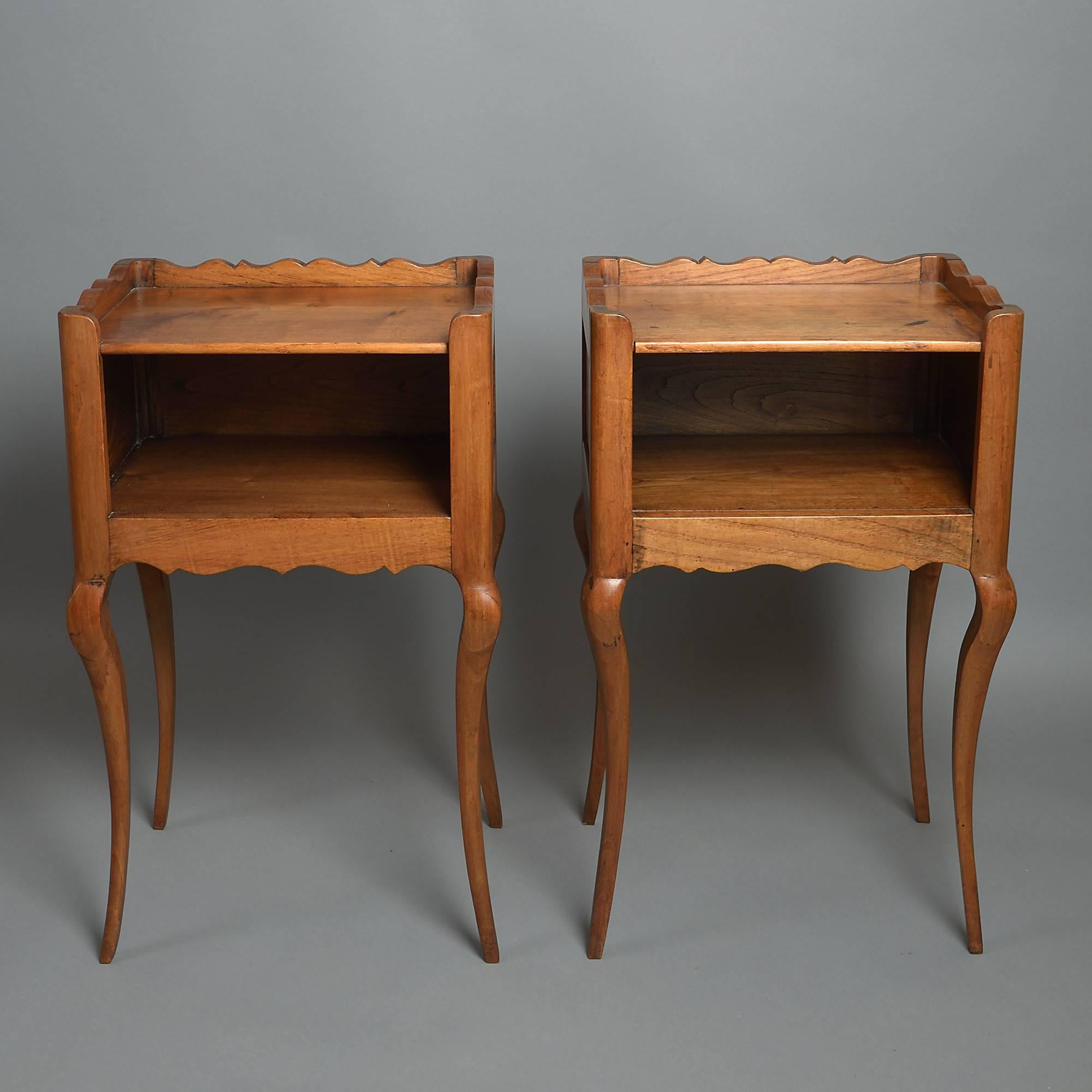 A fine early 20th century pair of bedside tables, the top shelves with shaped galleries above open compartments, the sides and backs with fielded panels, all set upon generously carved cabriole legs.