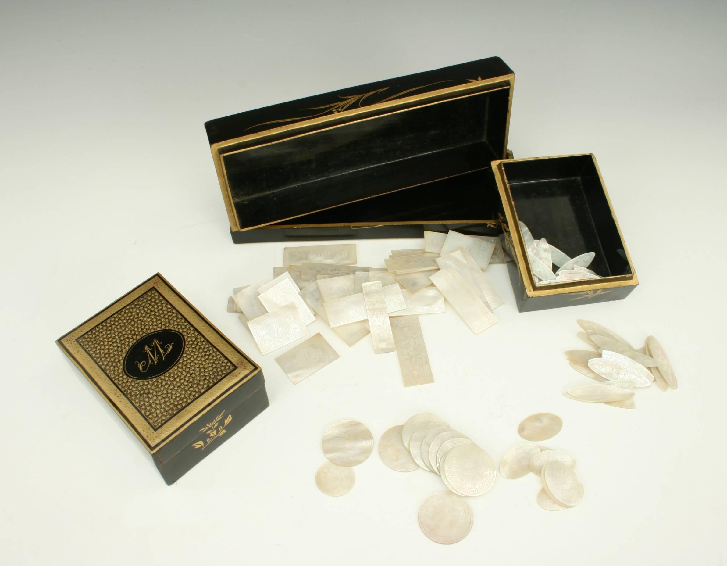 Chinese mother-of-pearl gaming counters. 
A 19th century Chinese black lacquer gaming box with the monogram 'W' on the lid and a collection of Chinese export mother-of-pearl game counters of various designs and sizes. The large box contains four