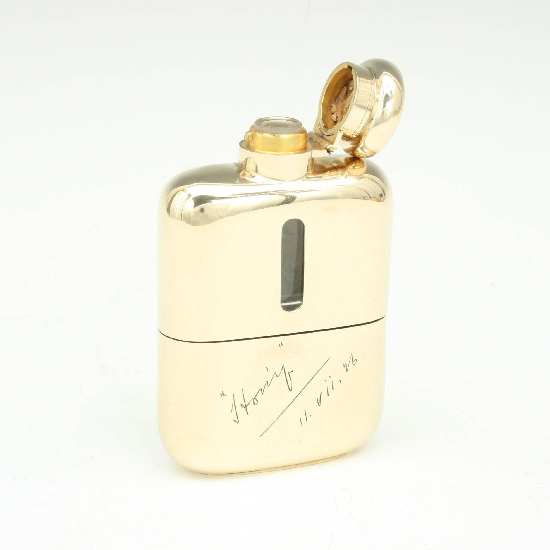 A high quality 9-carat gold and glass hip flask. The top half covered in gold with level viewing windows on both sides, the lower section a removable drinking cup. All gold marked "Goldsmiths & Silversmiths Co. Ltd." and, 9 for 9ct