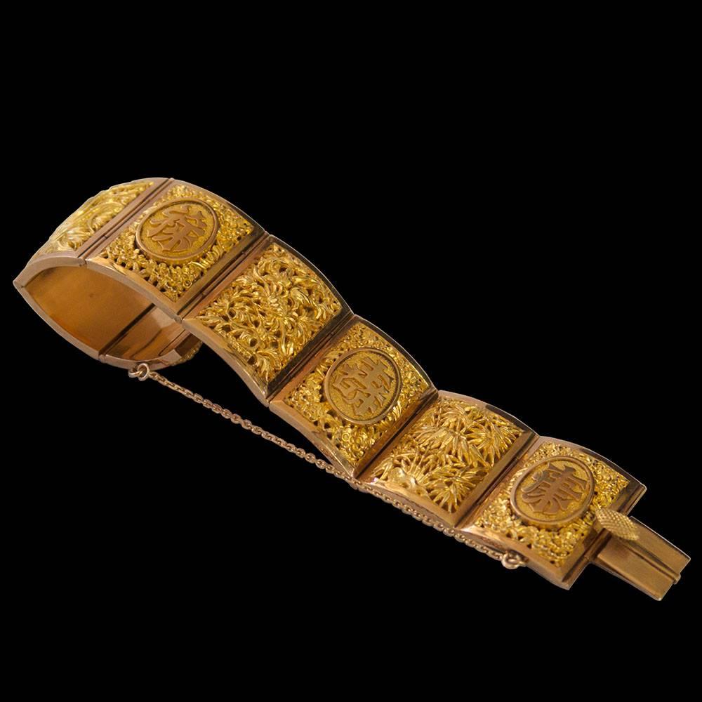 A beautifully worked gold bracelet formed of eight hinged rectangular panels, four depicting flowers representing the seasons and four with Chinese characters.