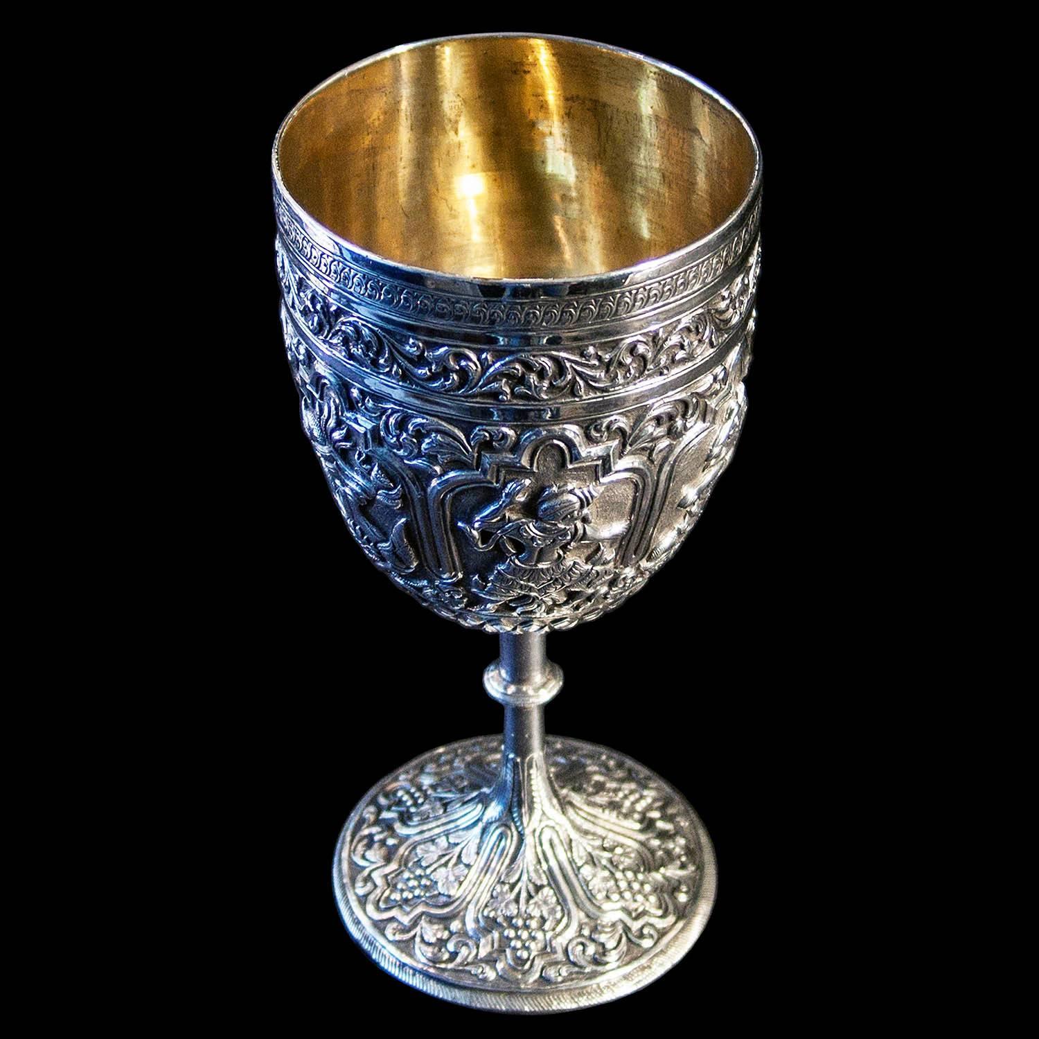 A heavy finely chased wine goblet with gilded interior. The surface of the cup embellished with figural panels.