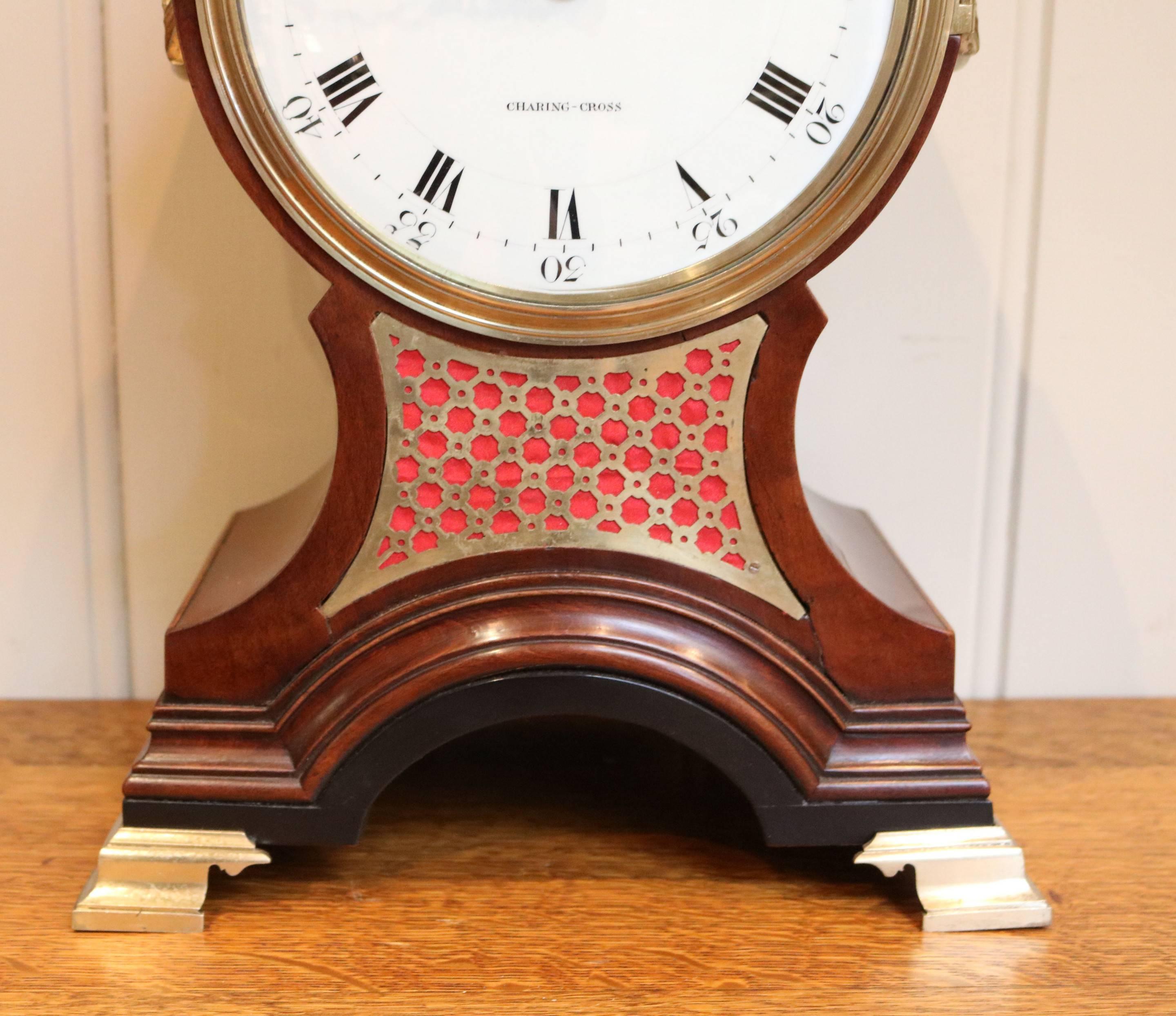 An impressive English balloon clock dating circa 1790. The mahogany case has a brass pineapple finial, brass carrying handles and a pierced brass front grill standing on substantial ogee bracket feet. The stepped brass bezel has a convex glass. It