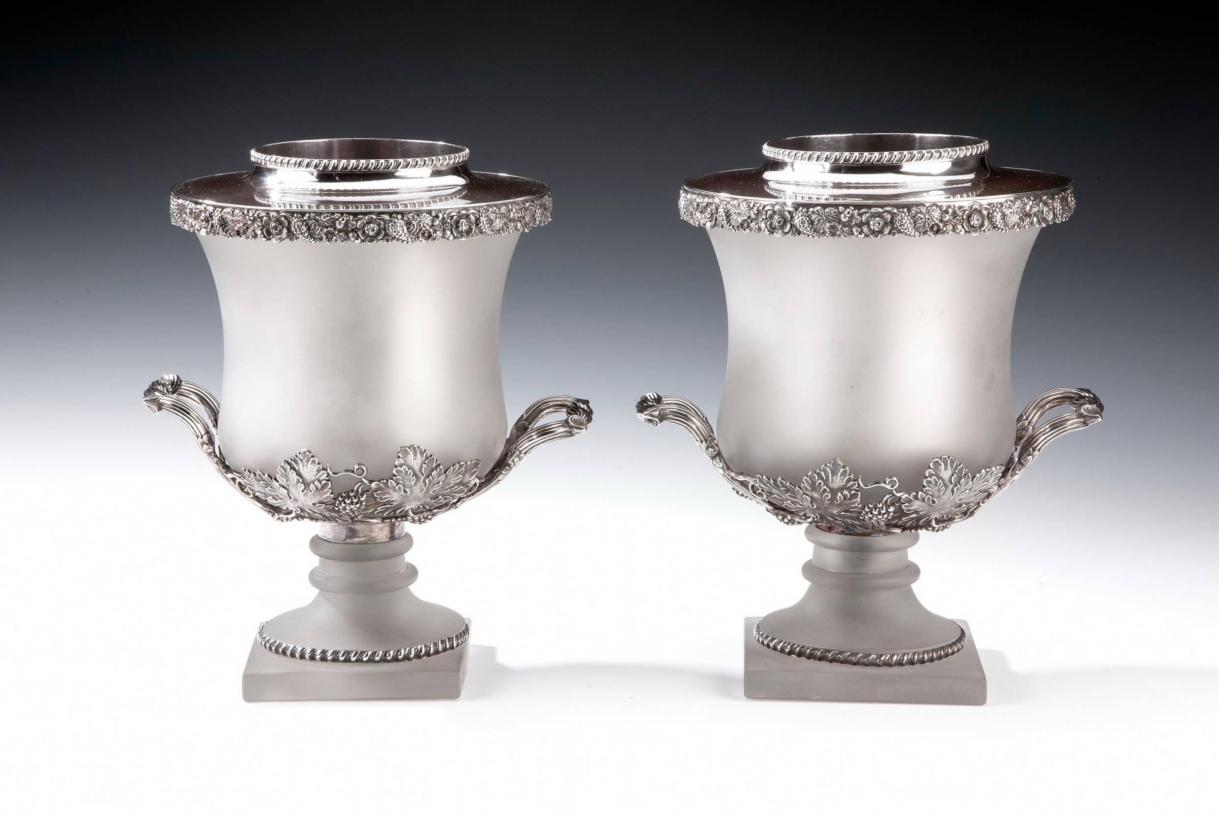 An unusual pair of frosted glass wine coolers, attributed to Collis & Co each of these unusual wine coolers comprises a shaped cylindrical glass body and pedestal foot set with silver plated mounts. The decoration consists of chased and repousse