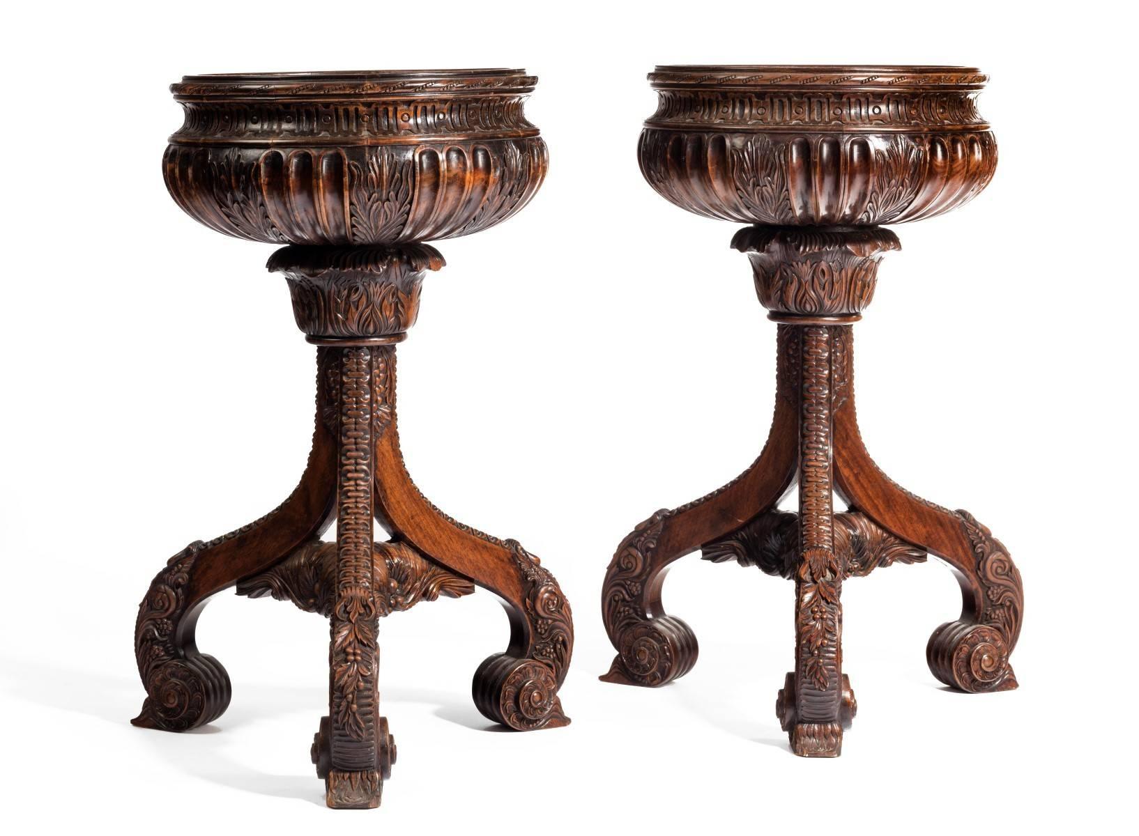 An outstanding pair of finely carved rosewood floor standing jardinières. Each raised on three out swept carved legs, which support a carved and fluted bowl. Each having a later copper and brass edged liner, Western India, circa 1840.