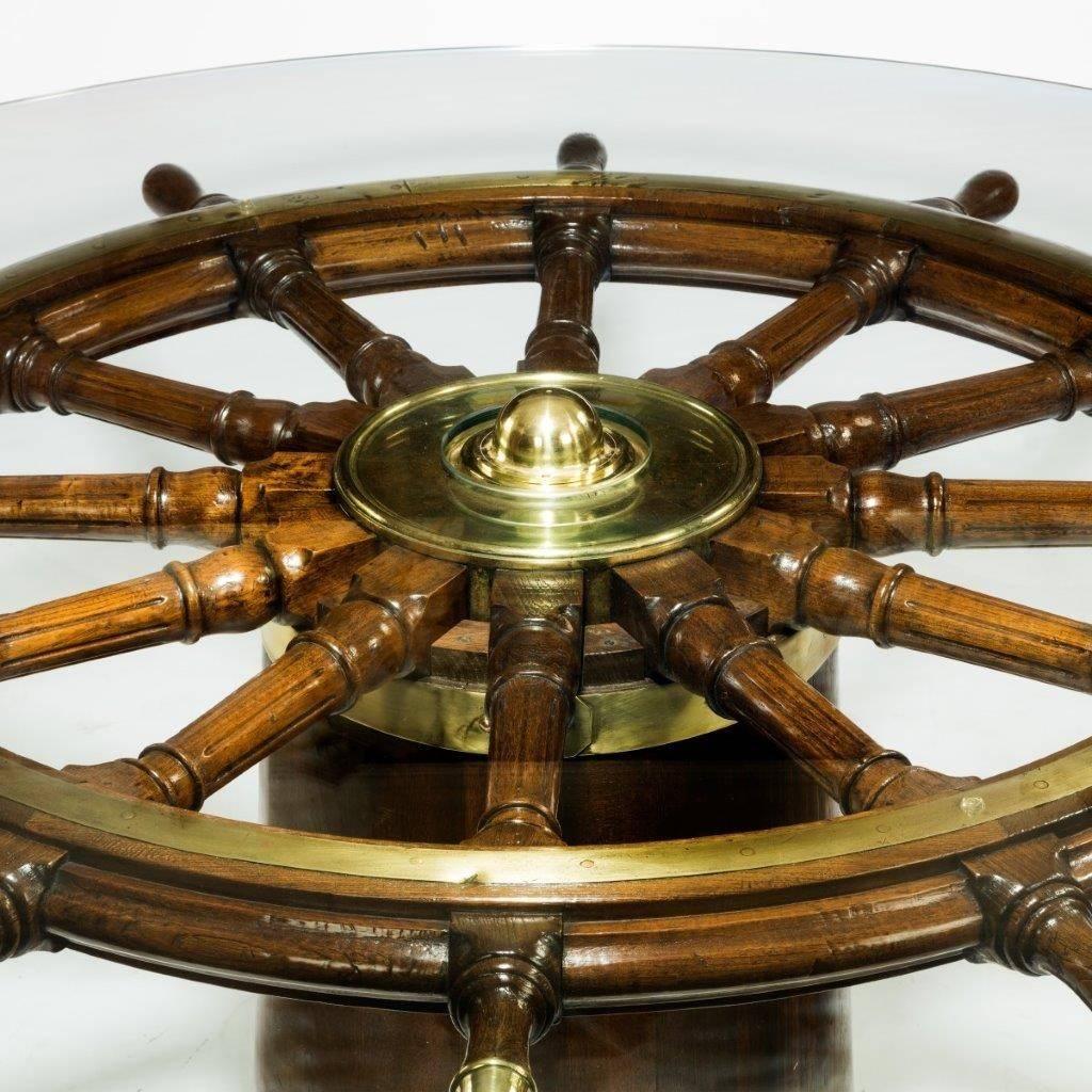 A very large table made from a late 18th century ship’s steering wheel,


from HMS Medusa, set on a brass bound teak binnacle. Modern glass top.


Measures : Height 30 ¼