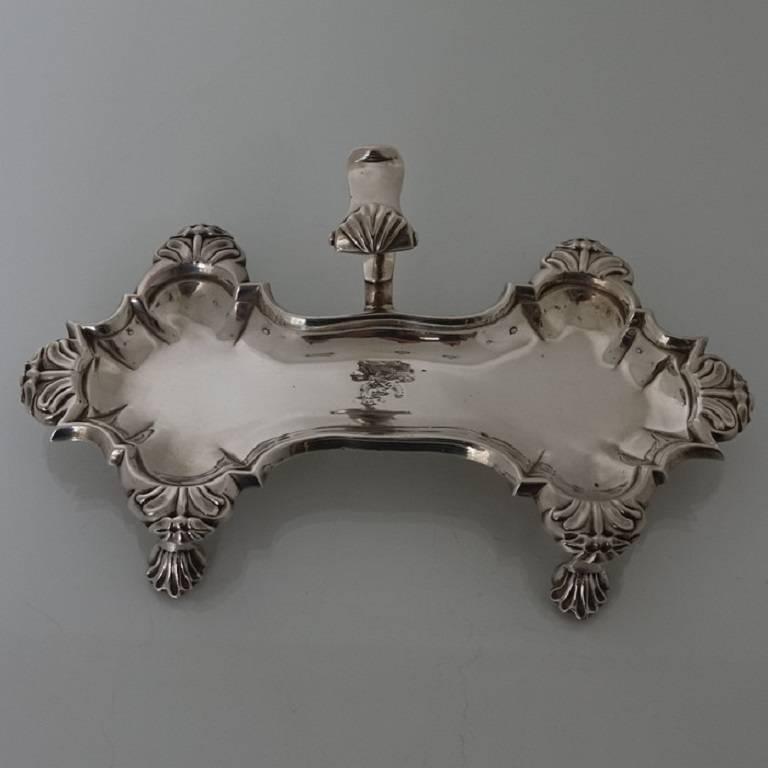 A very good quality and extremely stylish Georgian snuffer tray sitting on four ornate feet. The snuffer tray has an applied decorative raised handle with thumb piece. There is a contemporary hand engraved crest for importance. 

The length is 21
