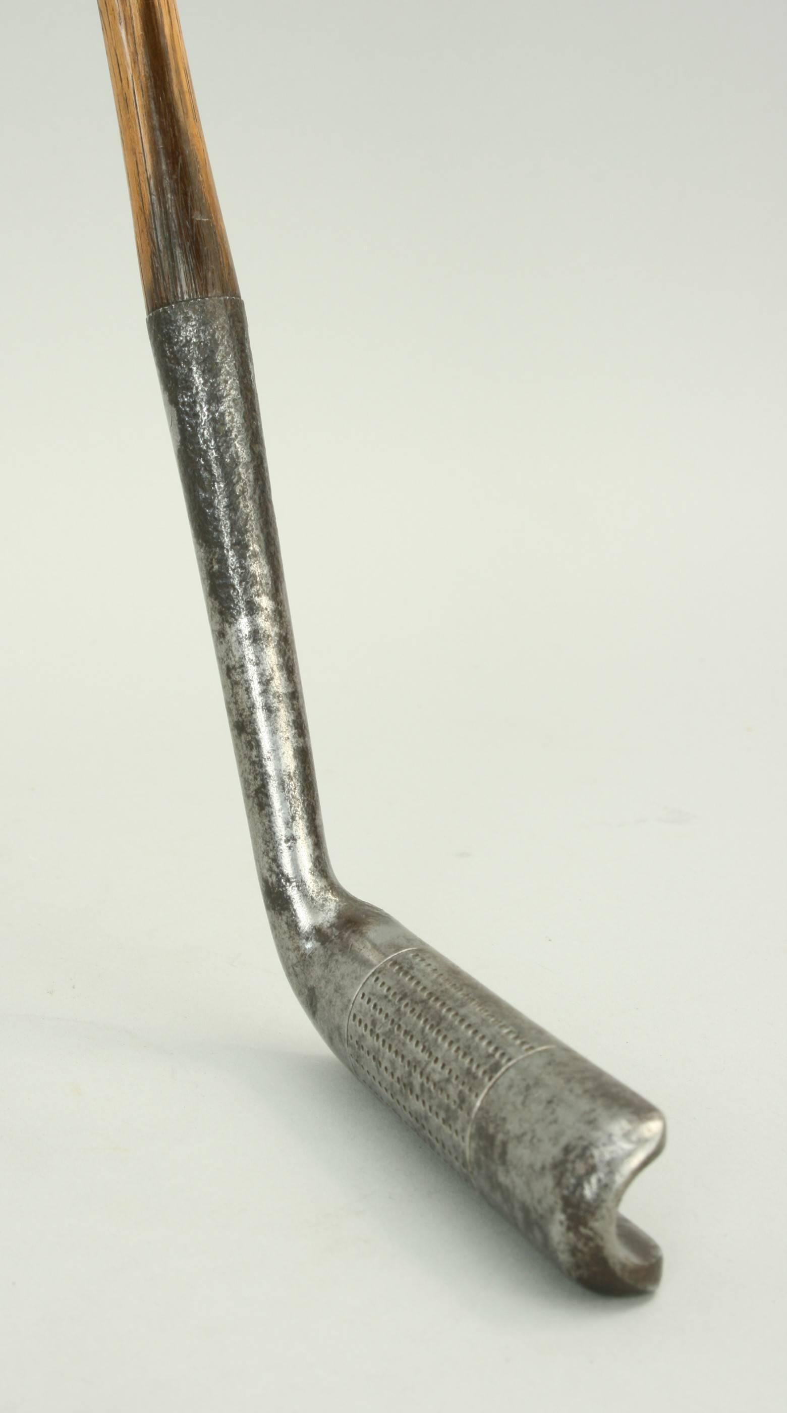 An unusual left-handed Perwhit putter by Hendry and Bishop with a cylinder face with hand punched face markings. The club has a hickory shaft with a polished leather grip. The recess in the back of the blade is stamped "The PerWhit Putter, Pat