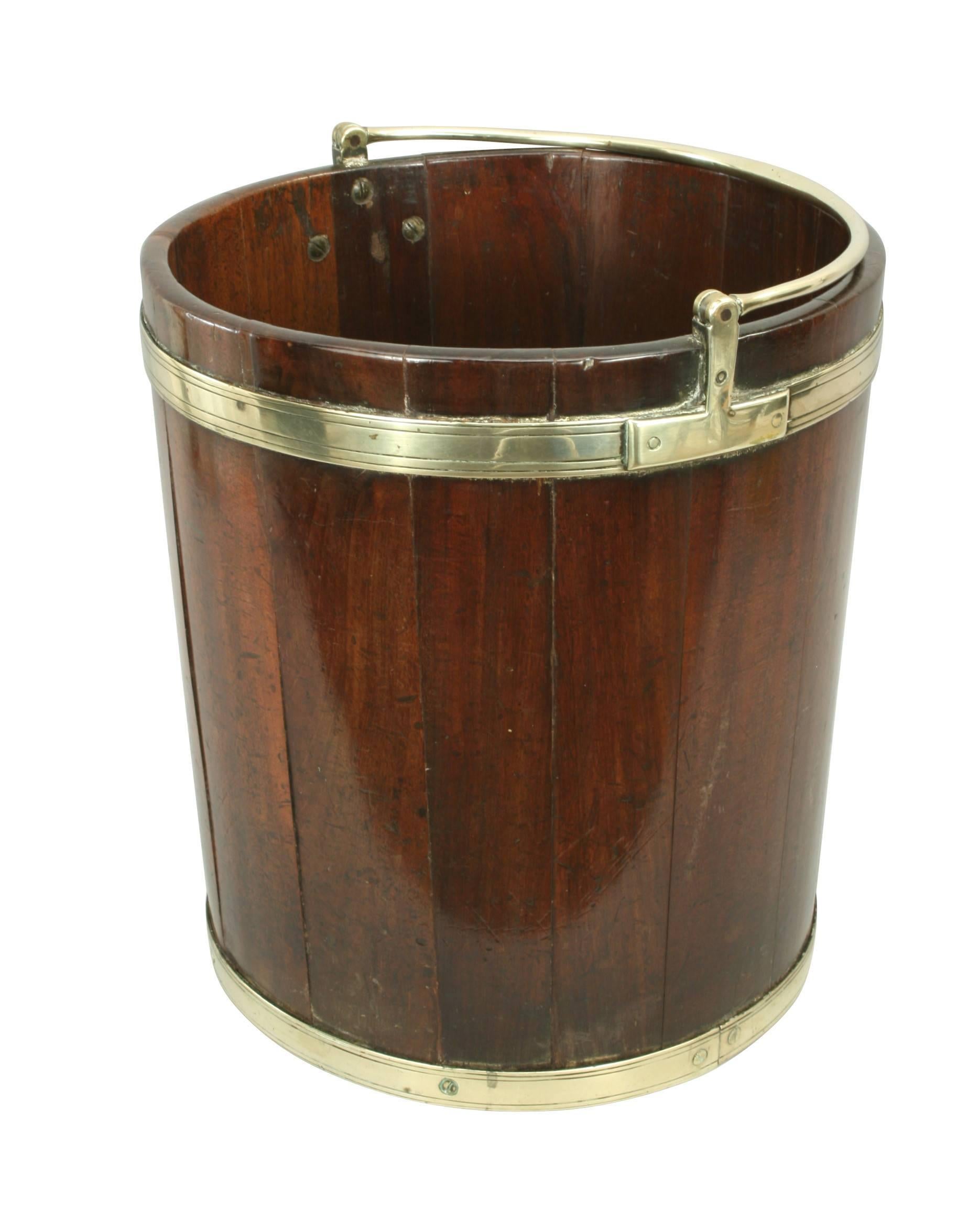 An exceptional good quality mahogany, brass bound peat or turf bucket in original color with exceptional patina. The bucket is of a coopered construction with two brass bands. The pivoting solid brass handle is attached to a decorative upper band.
