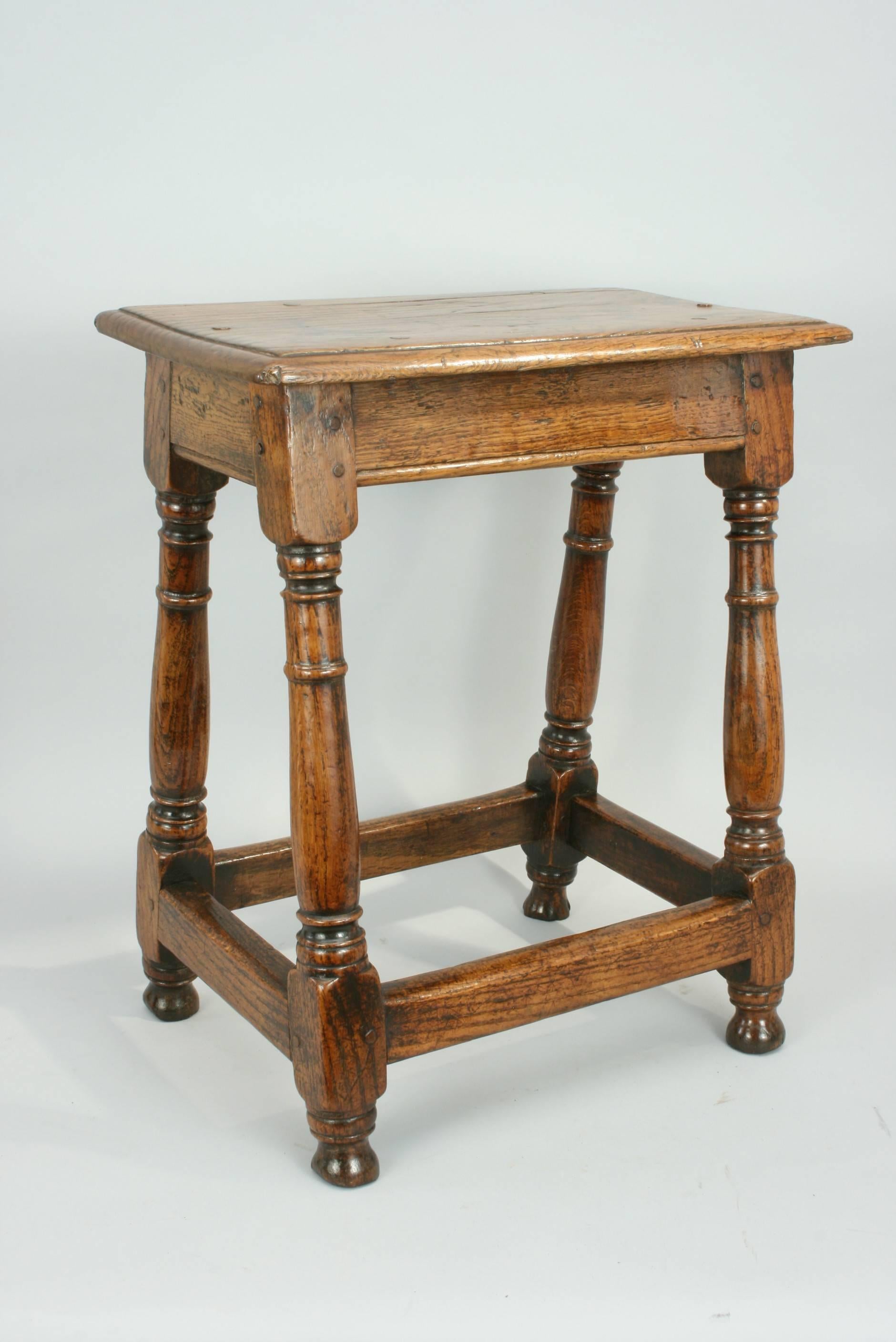 An early oak joint stool in original condition with wonderful colour and patina. The moulded rectangular top is pegged onto the base, which consists of moulded top rails, attractive baluster and peg turned legs with turned 'toes'. The legs are built