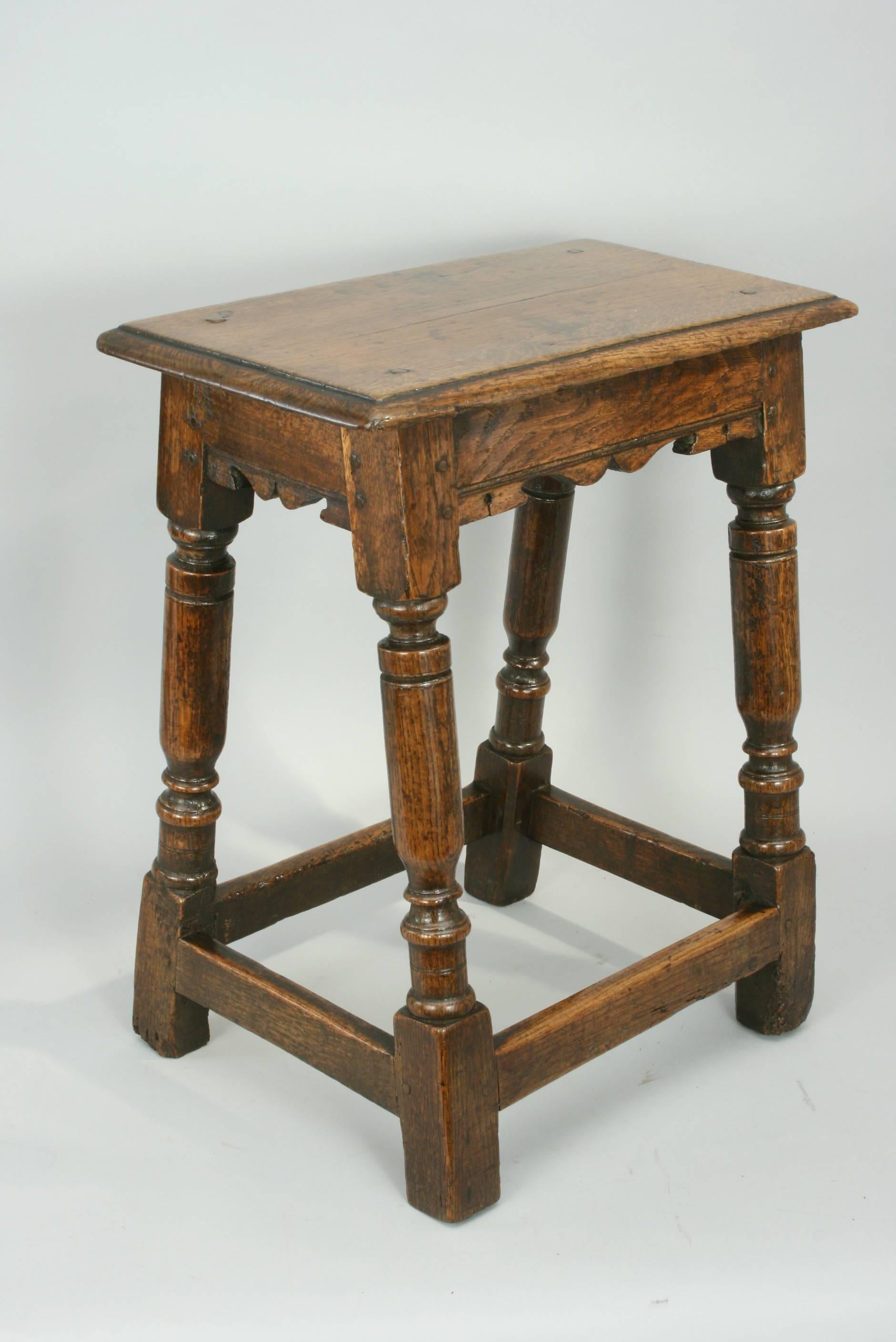 An exceptionally high quality early oak joint stool in original condition with wonderful color and patina. The moulded rectangular top is pegged onto the base, which consists of moulded and shaped top rails, attractive turned legs with square shaped