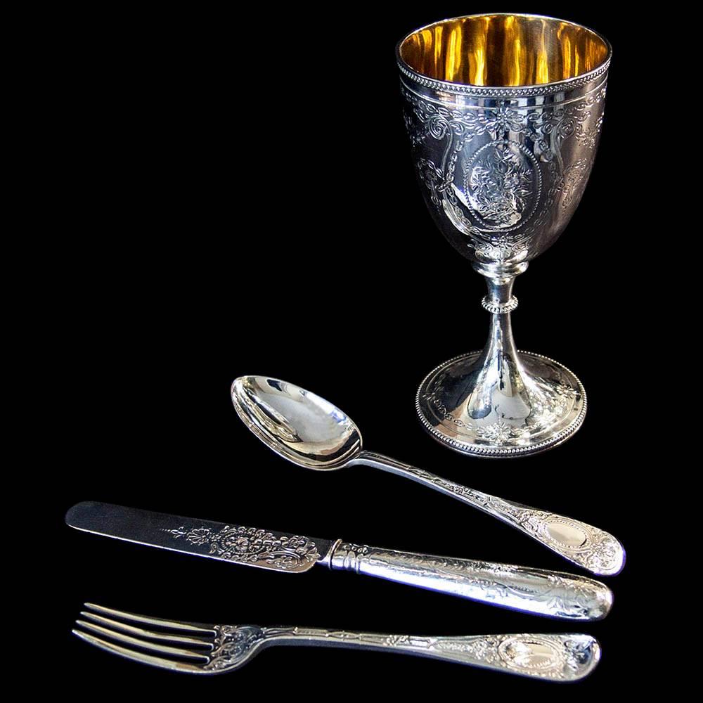 A Victorian silver christening set comprised of goblet, knife, fork and spoon. Each piece decorated with bright cut engraving in a floral design. The goblet further embellished with beaded borders and gilded interior. All in original presentation