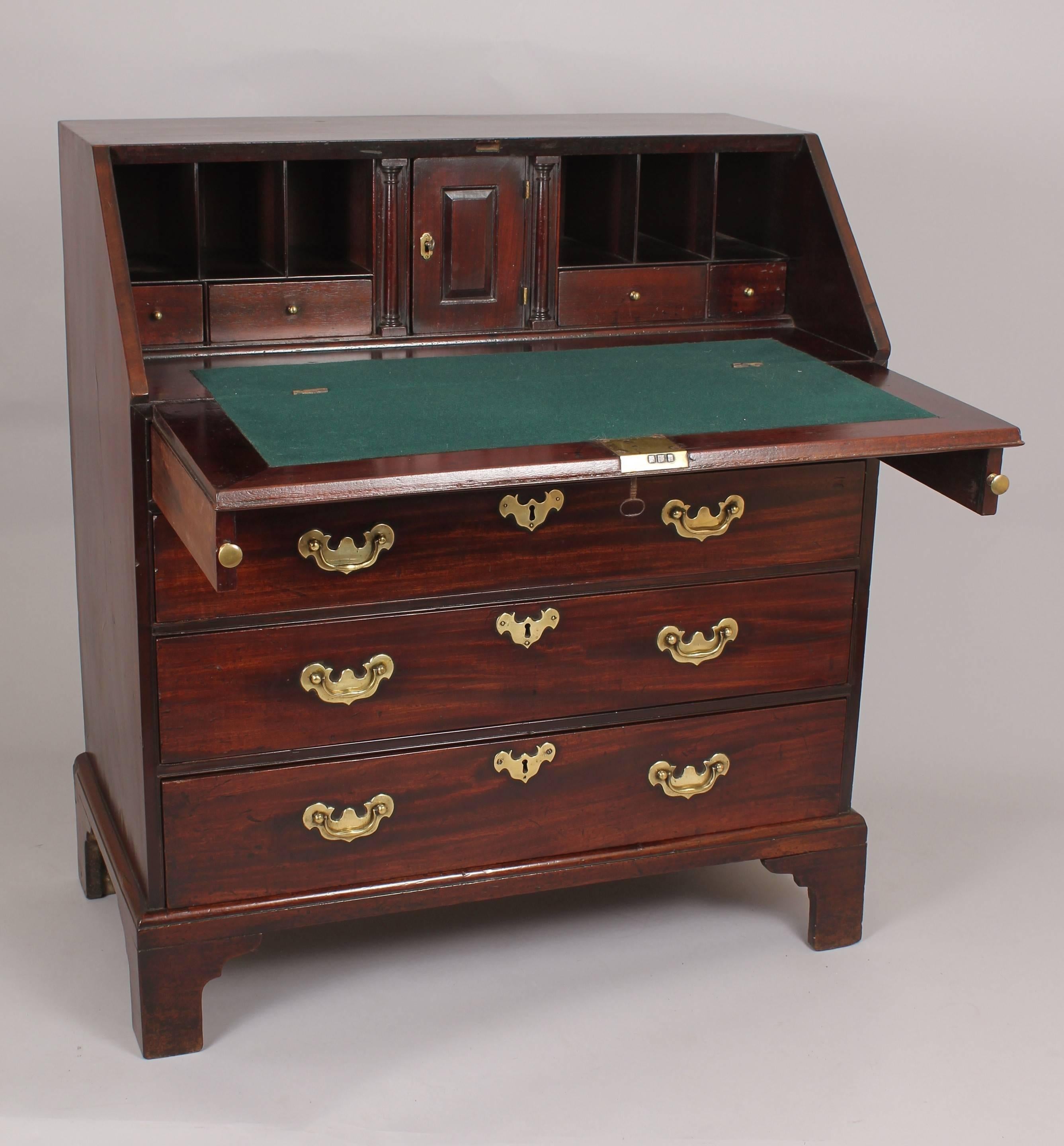 Early George III period mahogany bureau; the well-fitted interior with a central cupboard and 'secret' pilaster drawers, enclosed by a cleated flap; the lower part with four graduated oak-lined drawers with fine original brass-work.