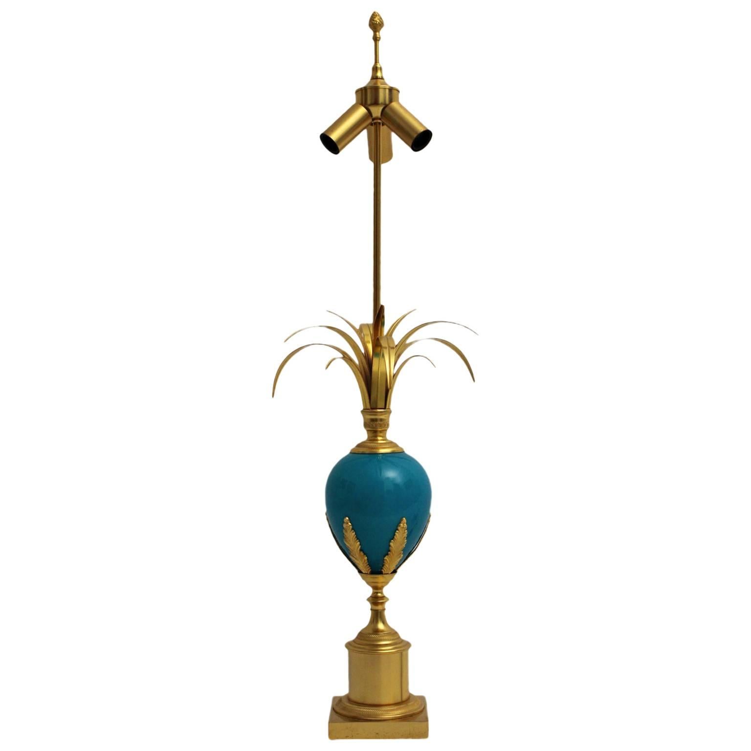 The Table lamp in the style of maison Charles is designed and manufactured circa 1970 in France.

The materials of the base is brass gilded and a turquoise glass egg decorated with brass gilded ornaments and stylized palm leaves. The lamp shade is